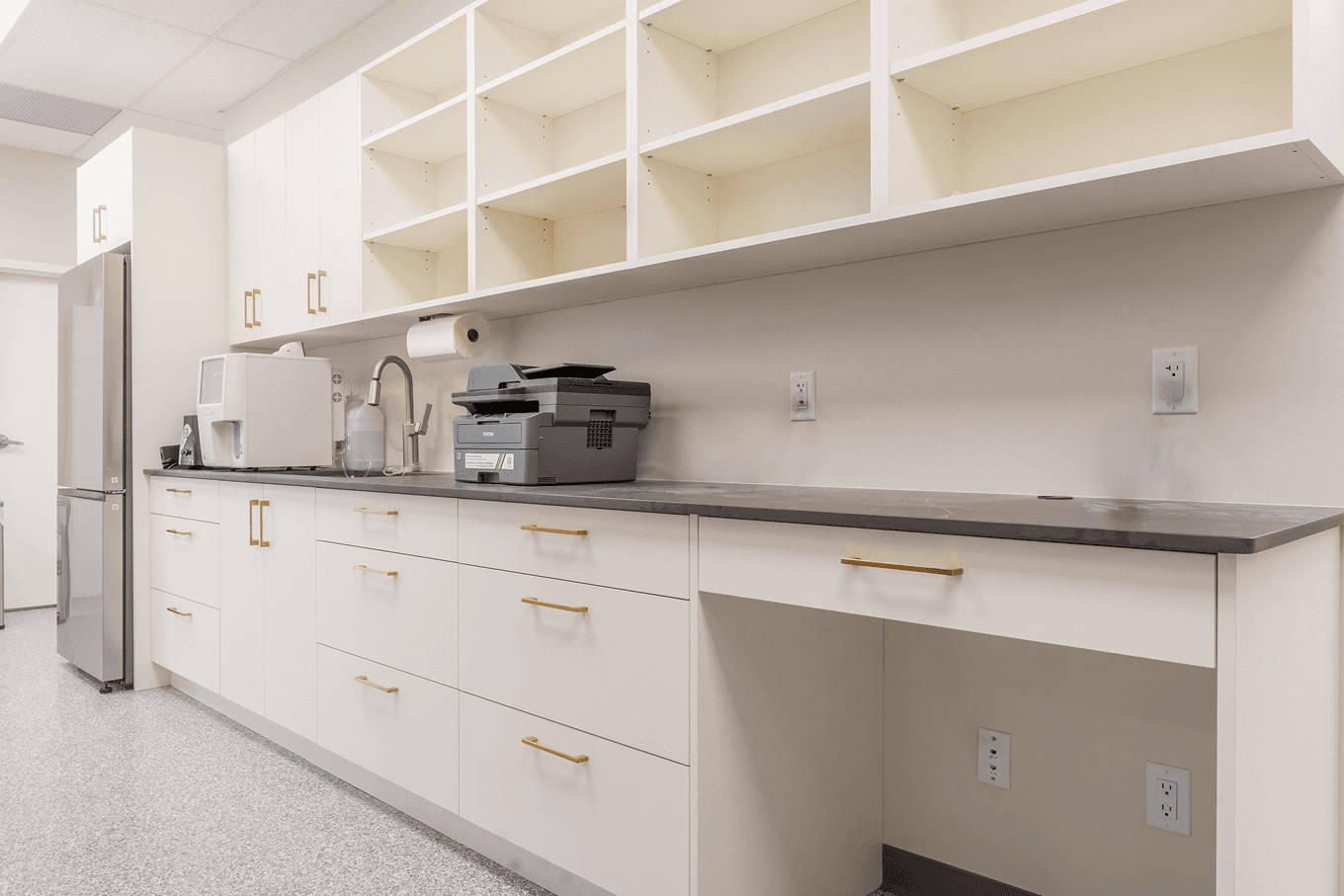 Long workstation with upper cubby storage, lower drawers, and integrated sink designed for clinical workflow.
