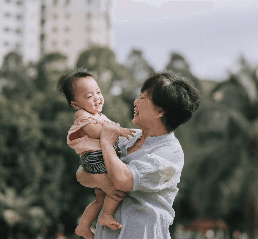 Grandmother holding baby smiling outdoors