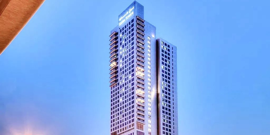 Sidra Tower at twilight with bright exterior lighting, showcasing high-end urban real estate at night.