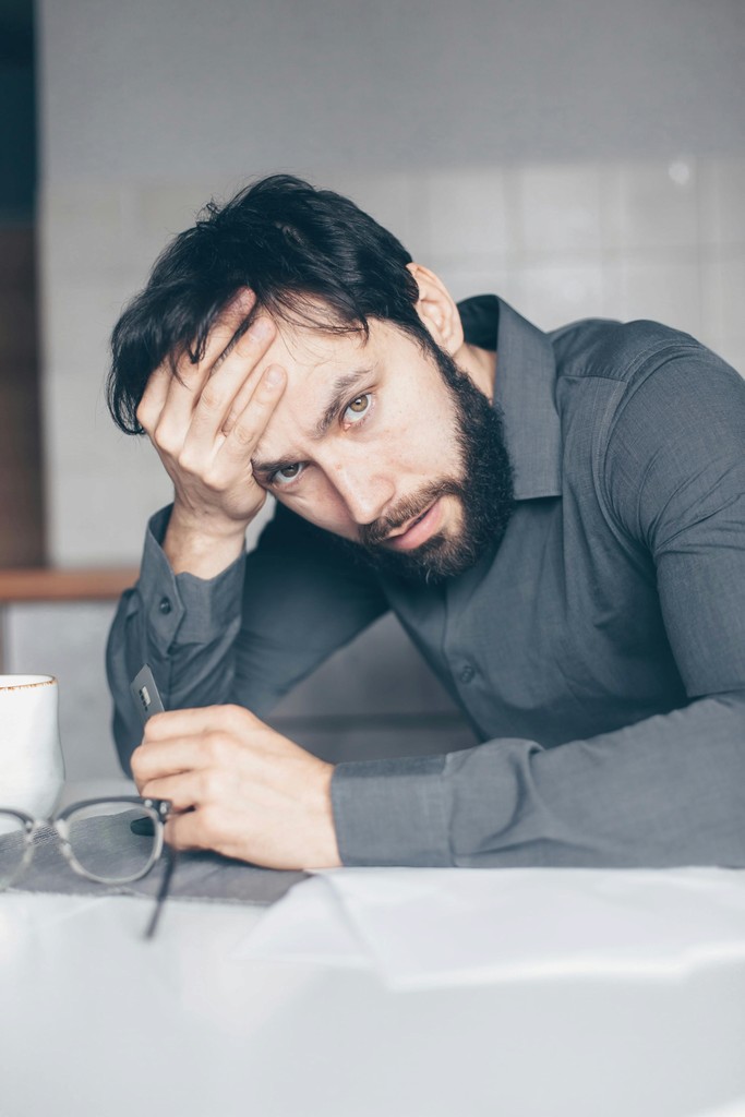 Stressed newcomer to Canada holding a credit card, representing the anxiety of falling victim to financial scams and identity theft.