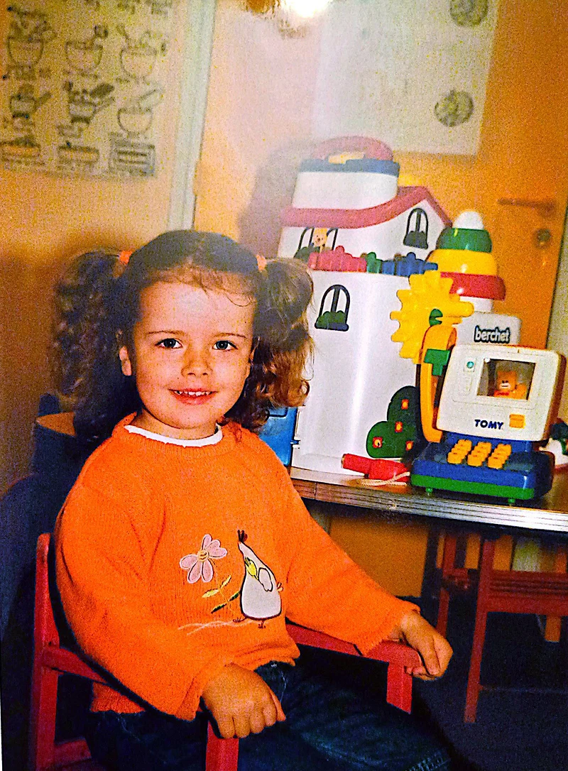 Maïlys quand elle était enfant. Elle est assise sur une chaise devant ses jouets.