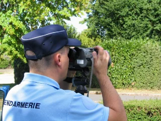 gendarme aux jumelles controllant la vitesse d'automobilistes