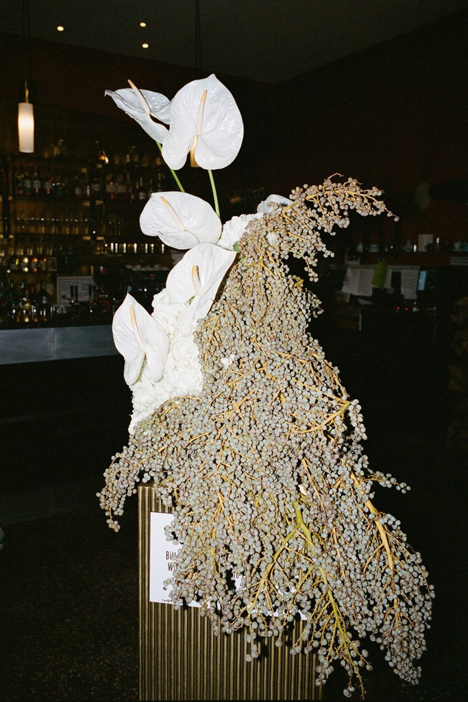 Flash image of flower installment inside a bar, draped vines and anthuriums