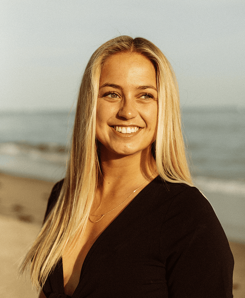 Portrait of Sarah Kowallik smiling on a beach at sunset