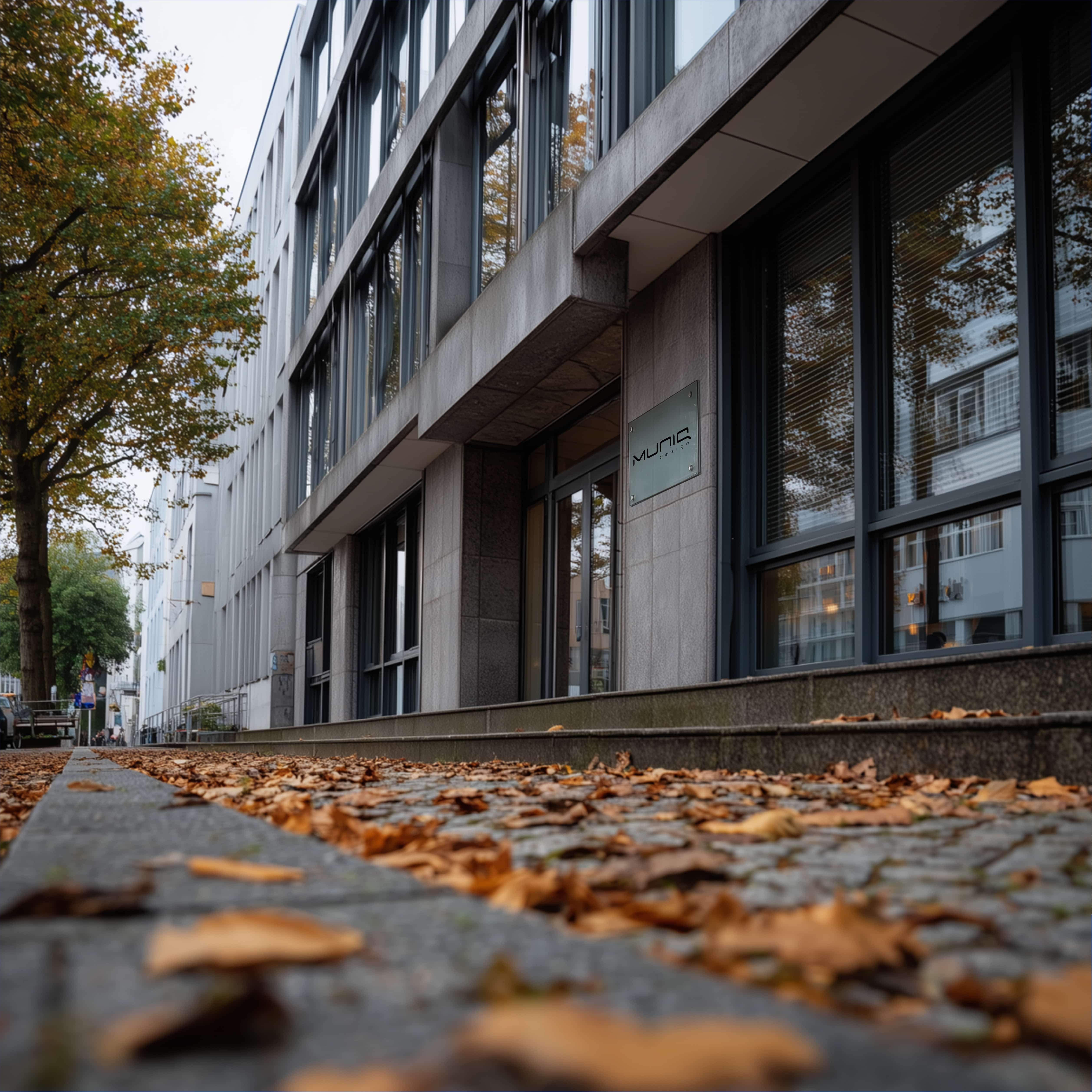 MUNiQ Design Berlin office building, showing the modern glass and concrete facade in an autumn setting. Focus on digital innovation and project scouting.