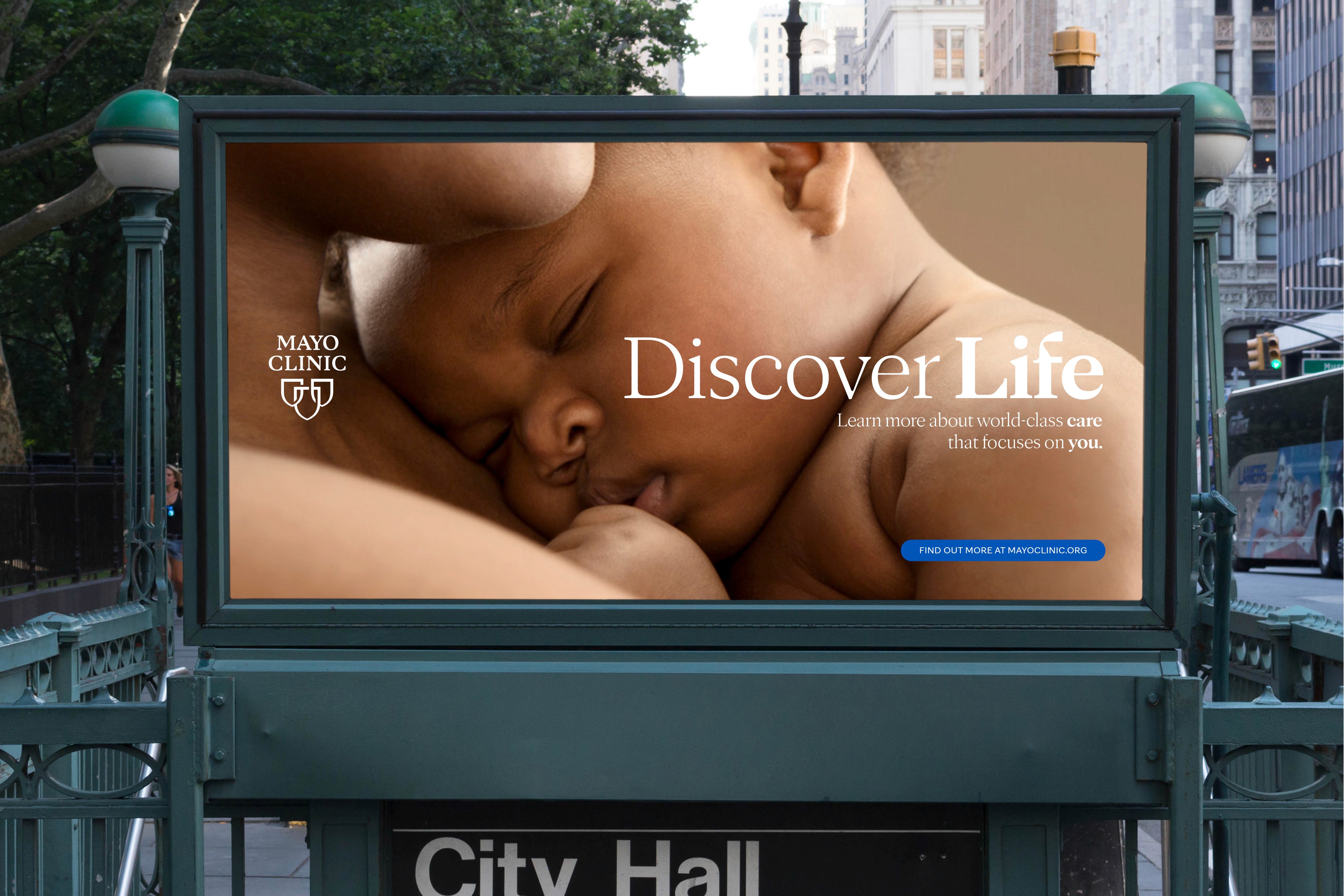 Close-up of a peaceful child sleeping, displayed on a city billboard with a backdrop of urban buildings.