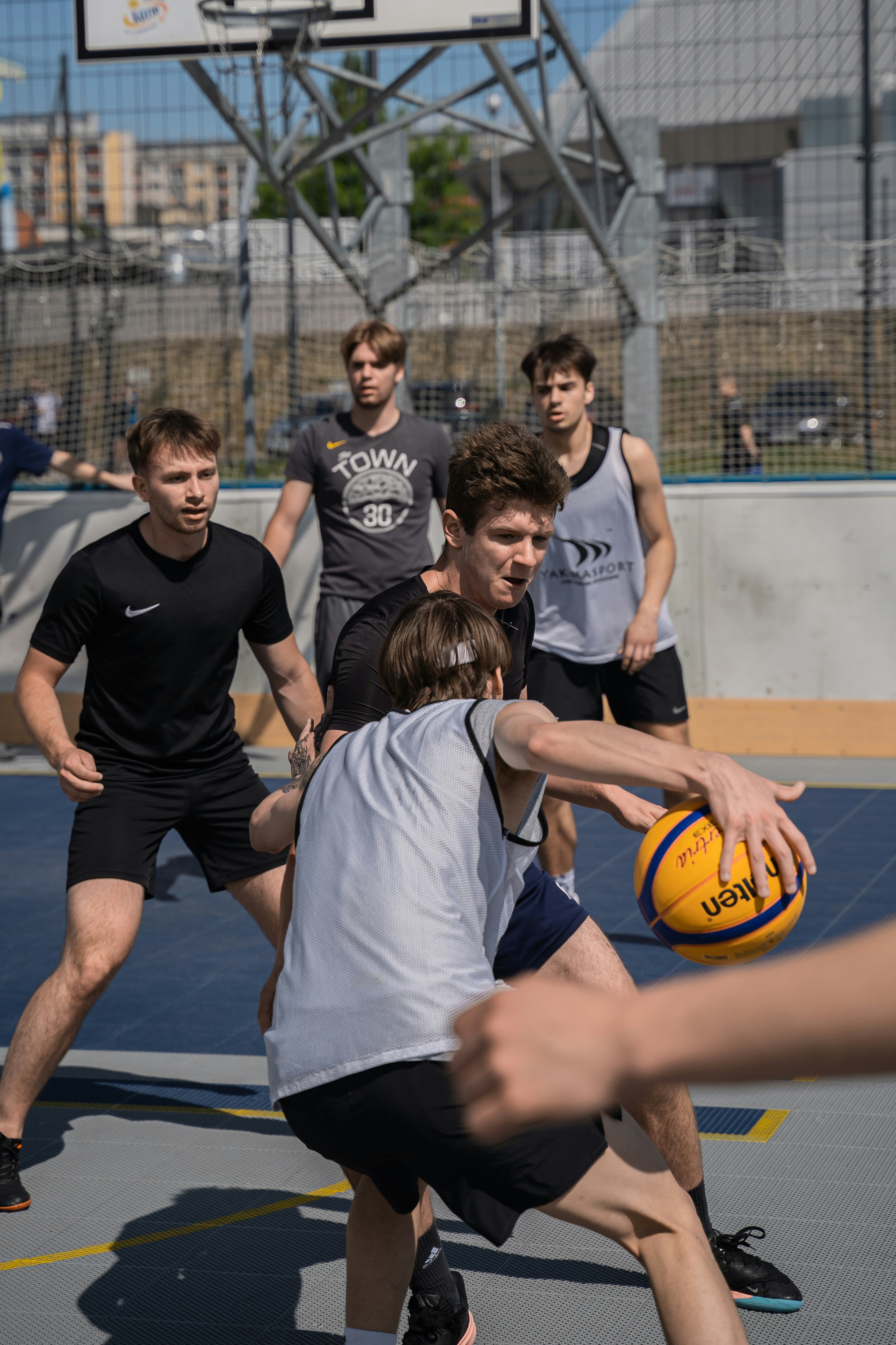 Basketball players compete in an outdoor street game.