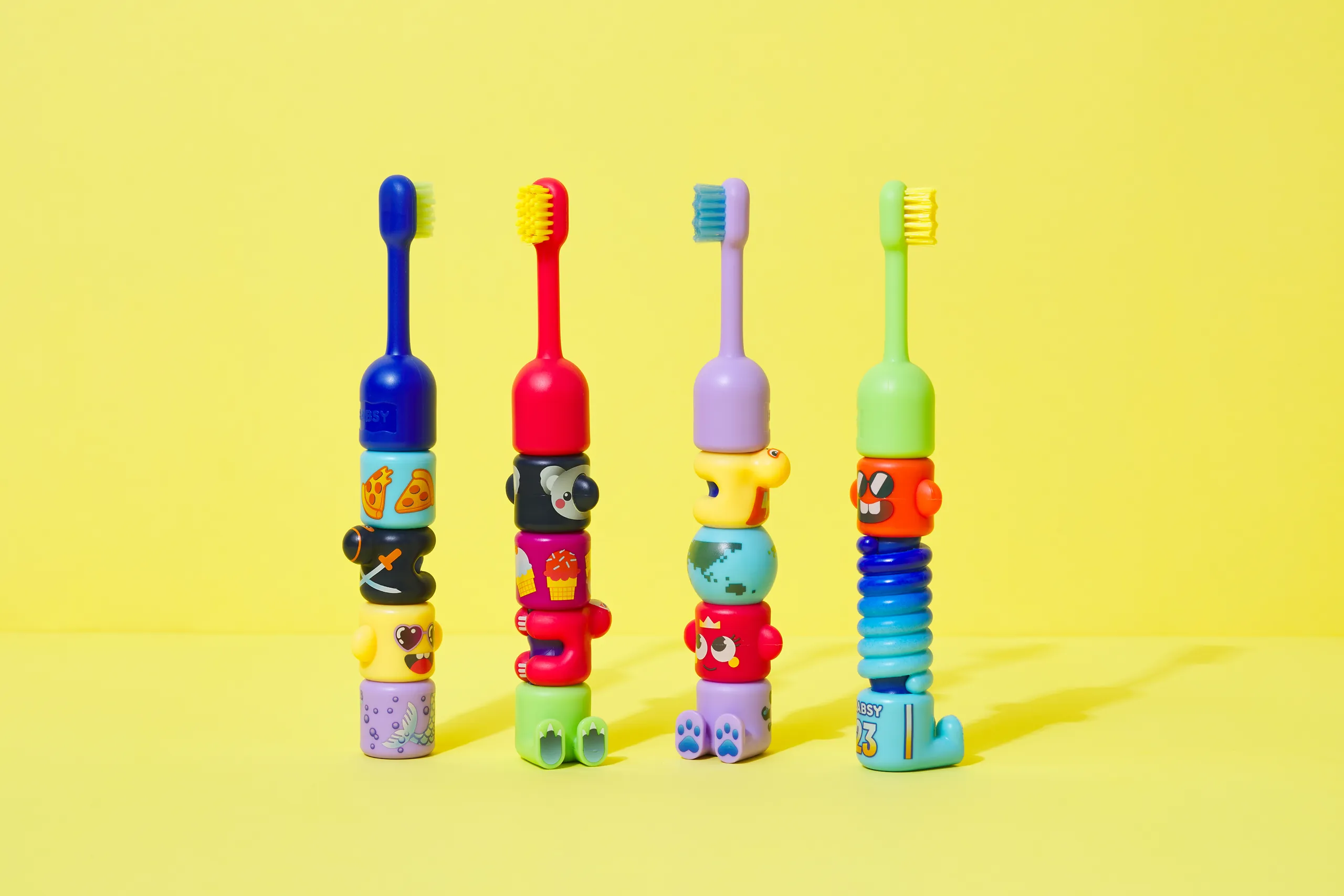Four colorful BABSY Build-A-Brush toothbrushes assembled with different character combinations