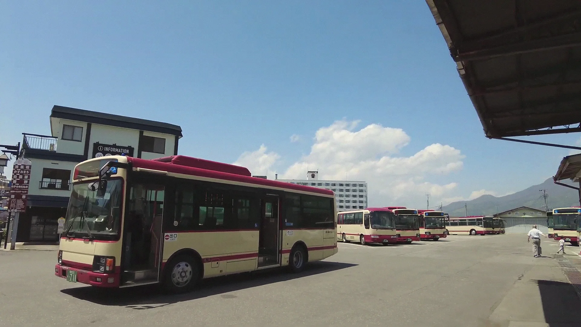 Red local bus at the Yudanaka depot under a clear sky