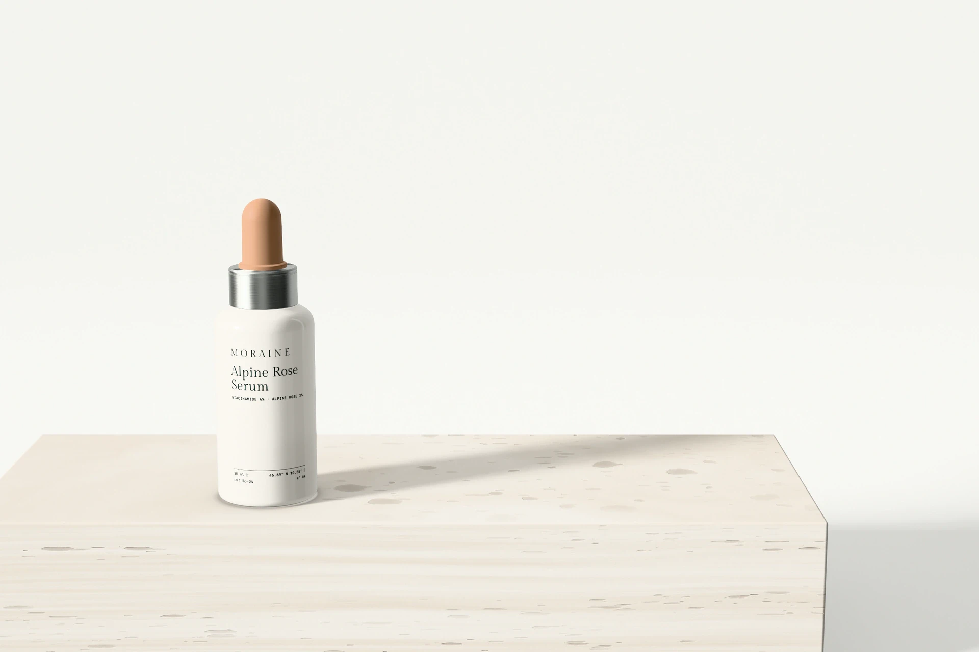 Alpine Rose Serum in an opal glass dropper bottle on a travertine block, with a long shadow