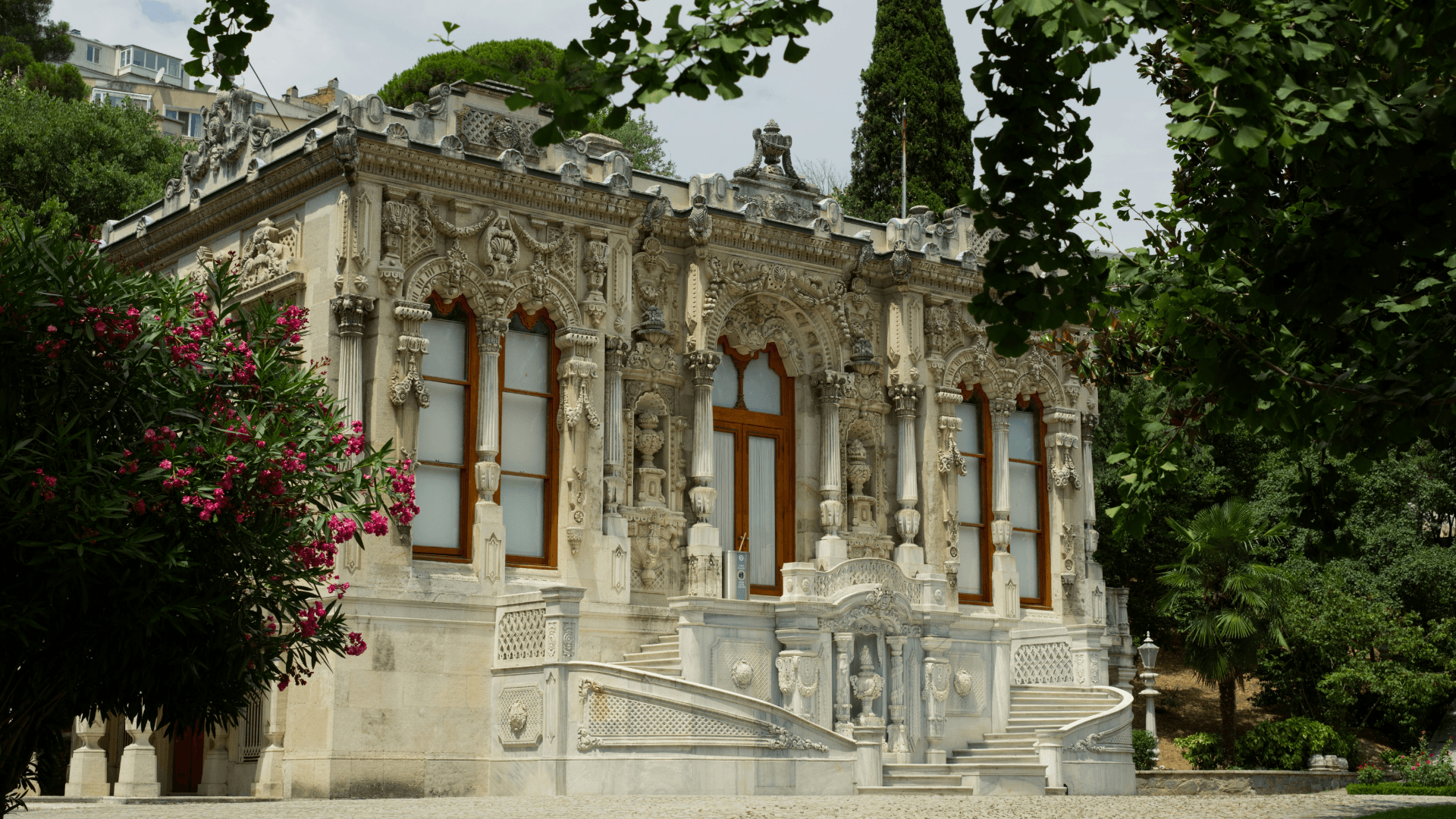 Ornate Ottoman pavilion surrounded by lush gardens in Istanbul, featuring carved stone details and historic architectural design
