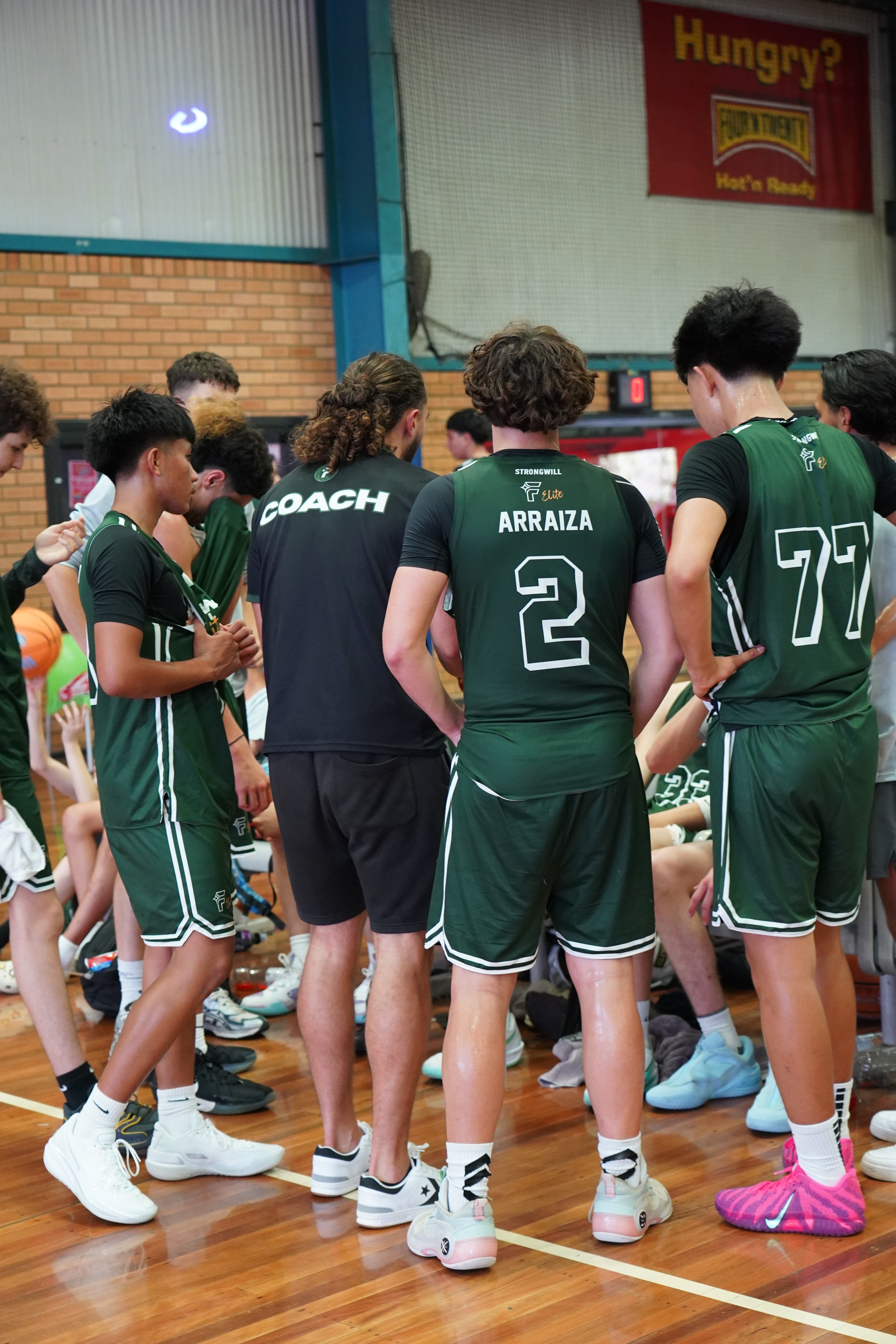 Free Flow Elite Basketball players engaged in a team huddle with their coaches.  