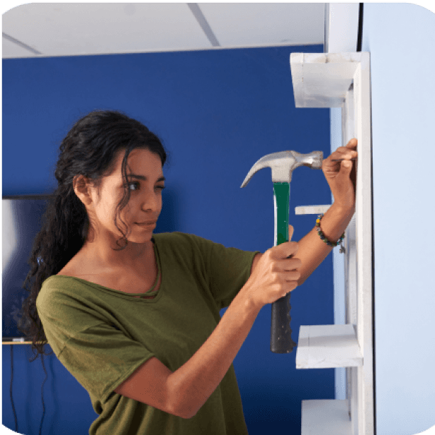 Woman installing a shelf with a hammer.