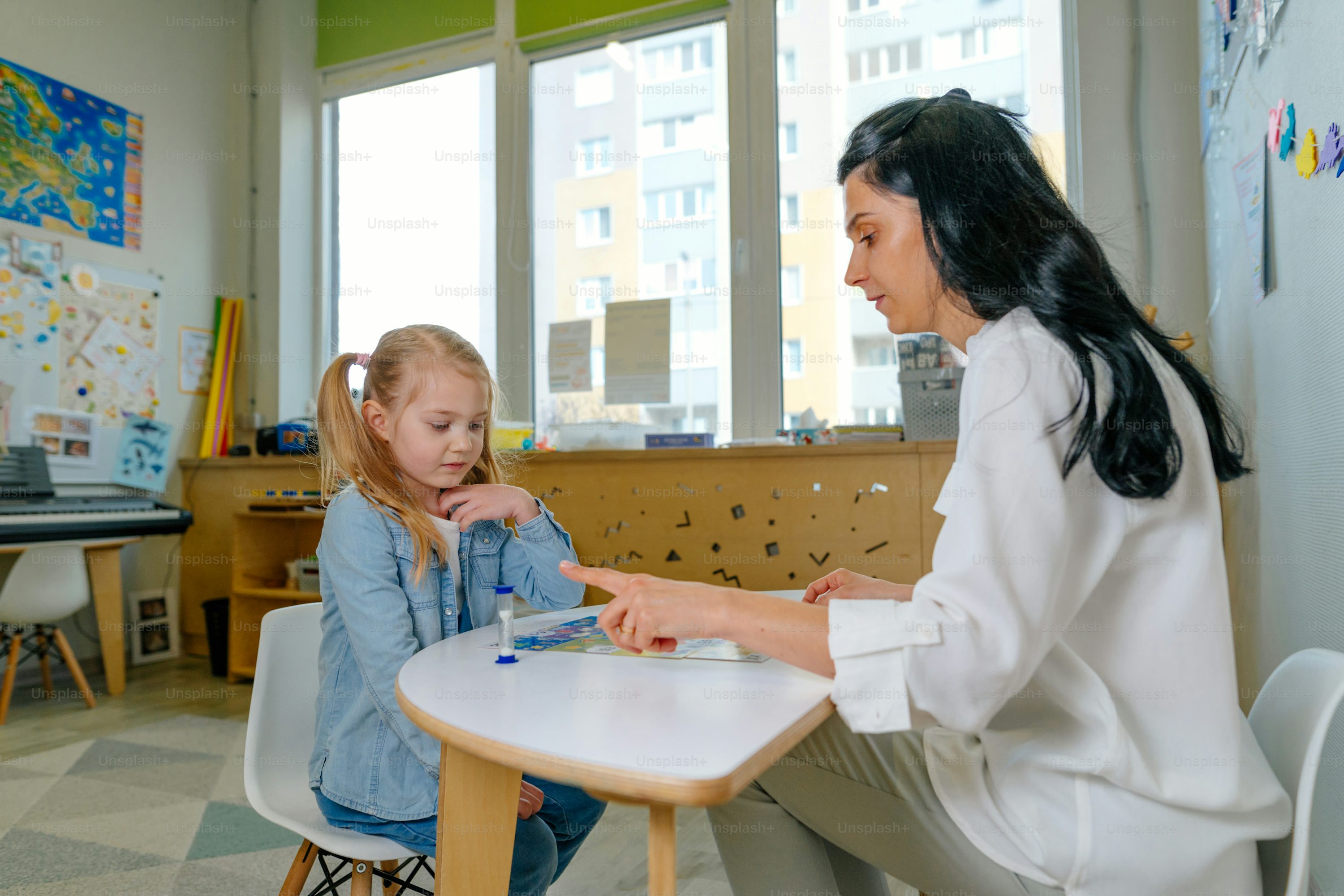 A young girl working on a puzzle with a therapist in a warm, well-lit learning setting.