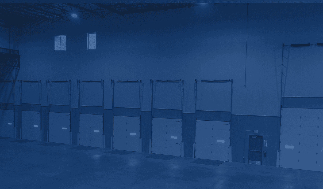 Warehouse interior with a row of insulated dock doors, yellow bollards and a polished concrete floor