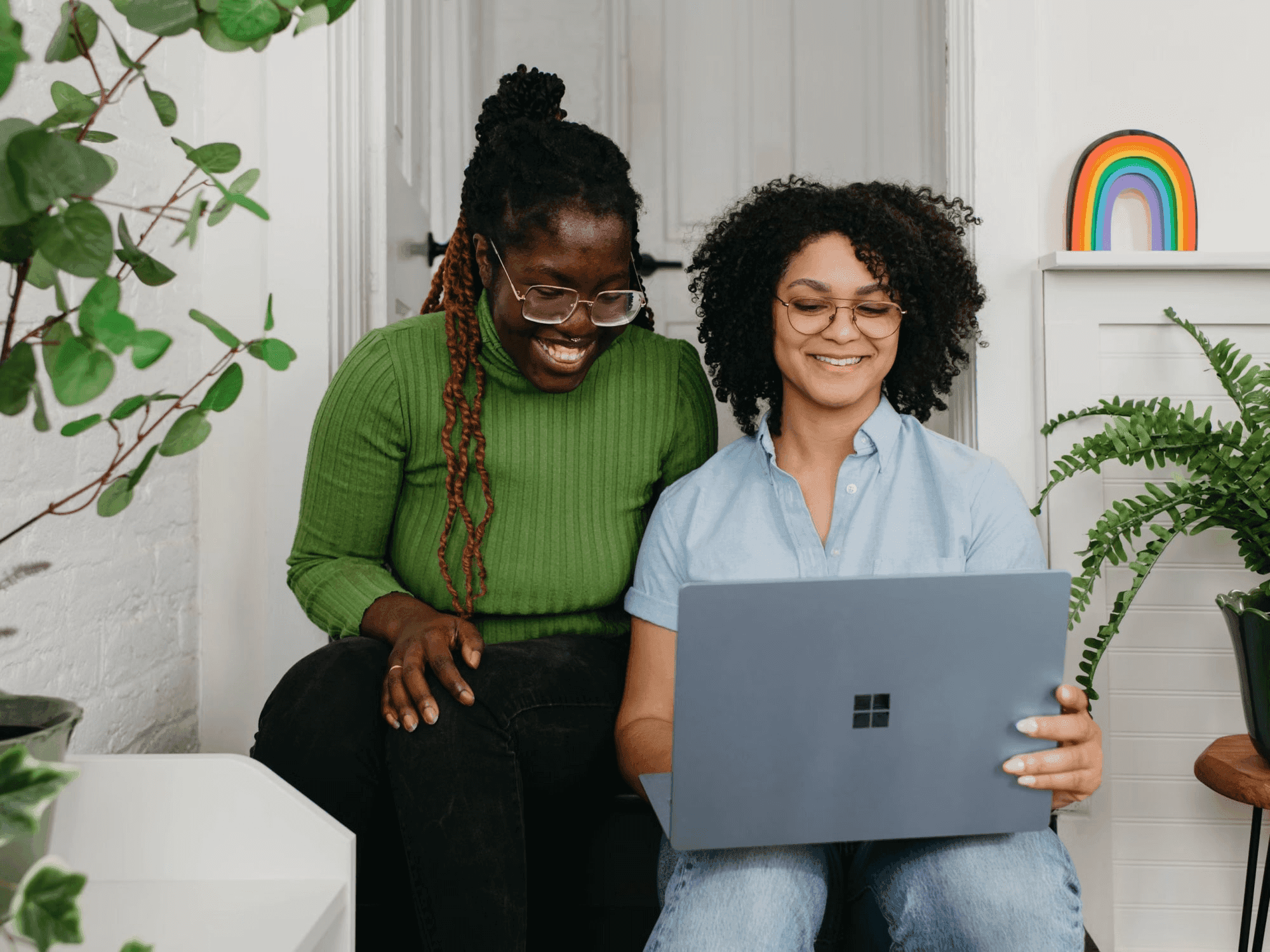 Two women seated on a couch, using a laptop to open a business bank account in the Netherlands with GoDutch.