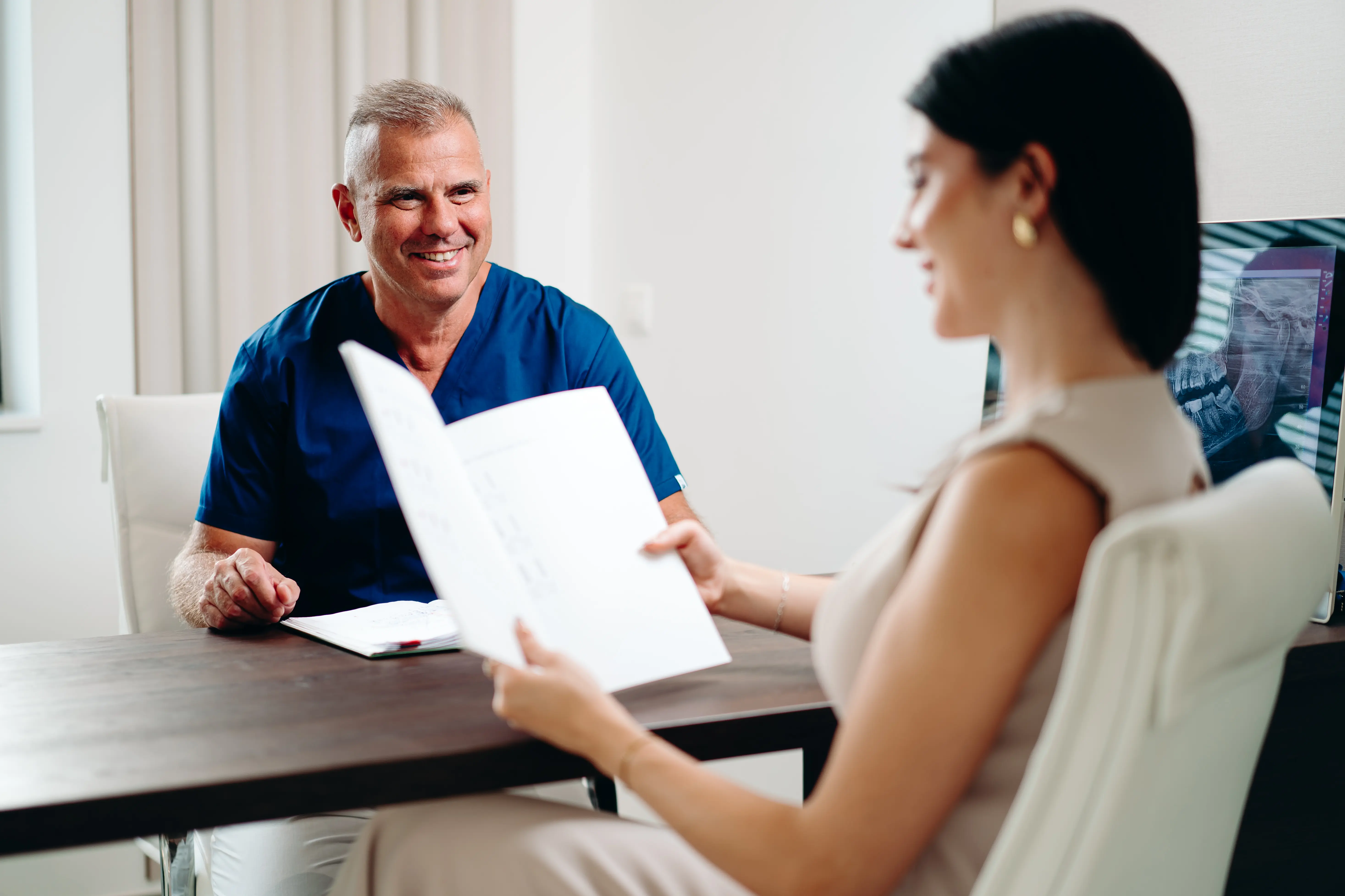 Fogorvos átadja a páciensnek a kezelési tervet egy rendelőben.