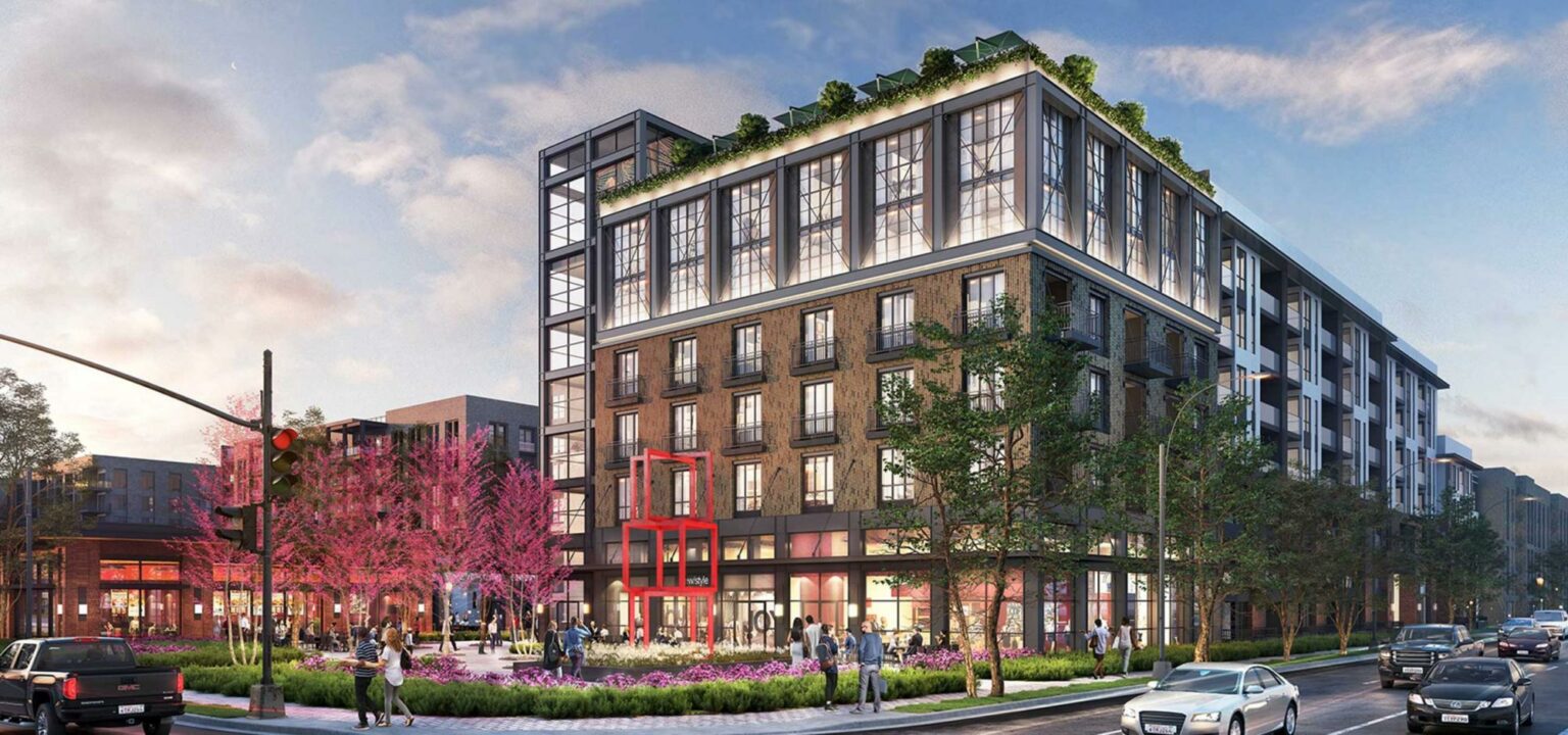 Street-level view of a modern mixed-use mid-rise building with large glass windows, brick facade, and a vibrant public plaza, protected by M-Fire Suppression.