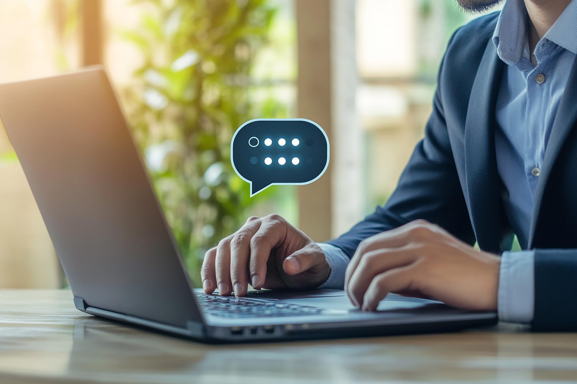 Man typt op laptop met chatballon-icoon