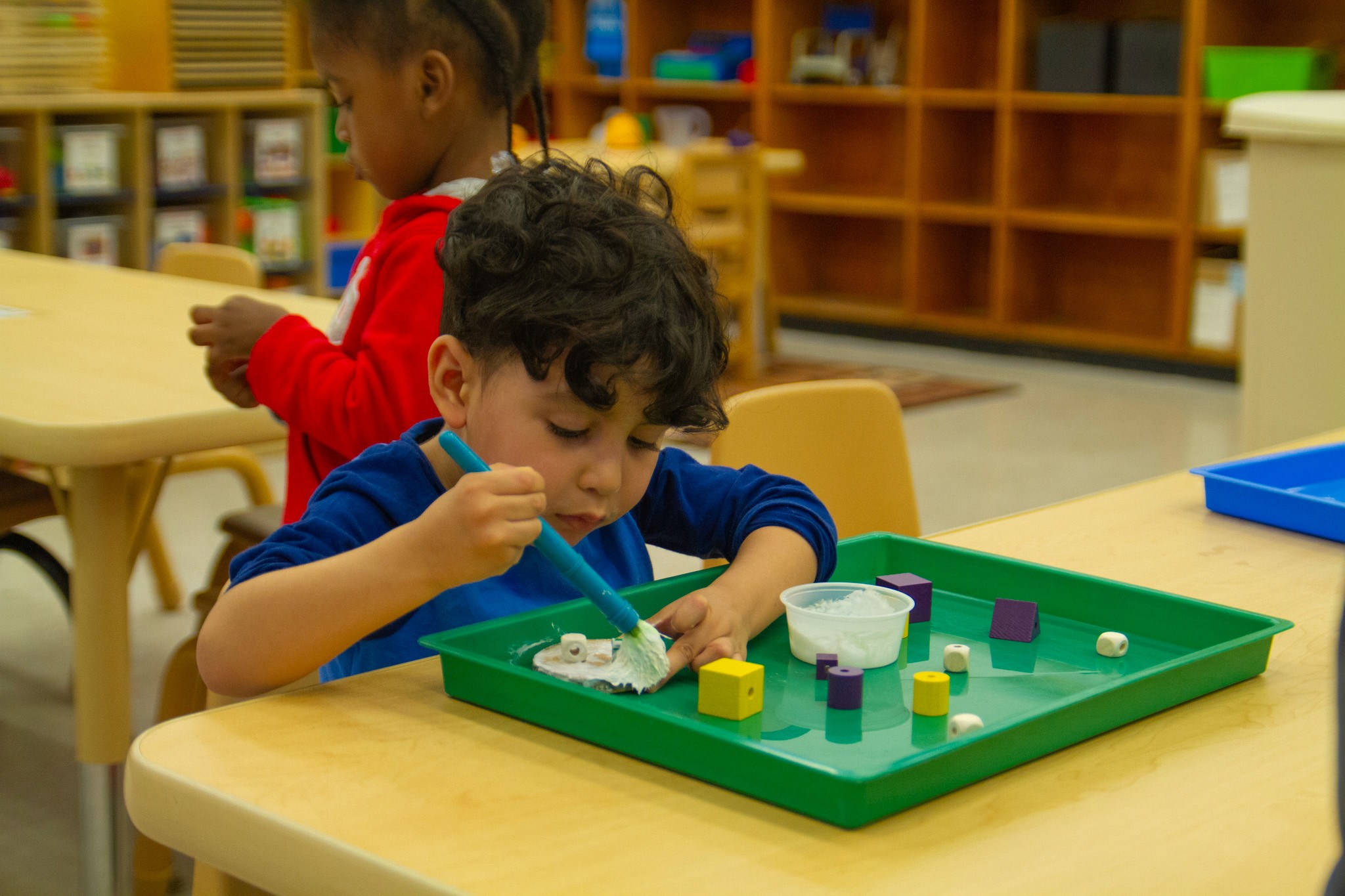 A young child doing arts and crafts in a classroom