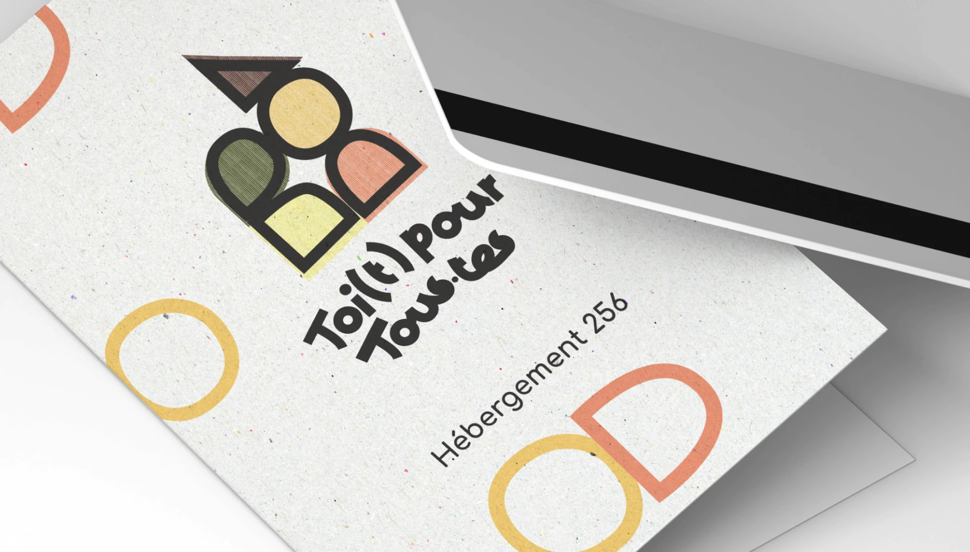 Mockup d'une carte d'accès et papeterie pour le lieu solidaire Toi(t) pour tous.tes. Identité visuelle éco-conçue sur papier recyclé, réalisée par la graphiste Tartelette Concept.