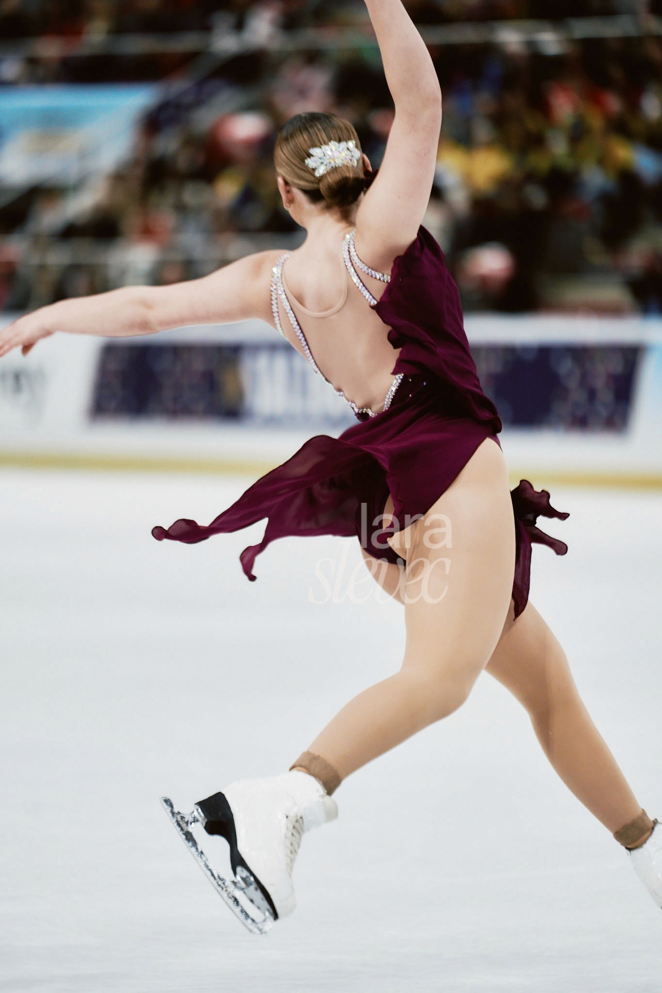 Eiskunstläuferin von Hinten in der Luft während eines Sprungs. Team Skyliners. ISU Synchronized Skating Championships 2026 in Salzburg. Fotografiert von Lara Slevec.
