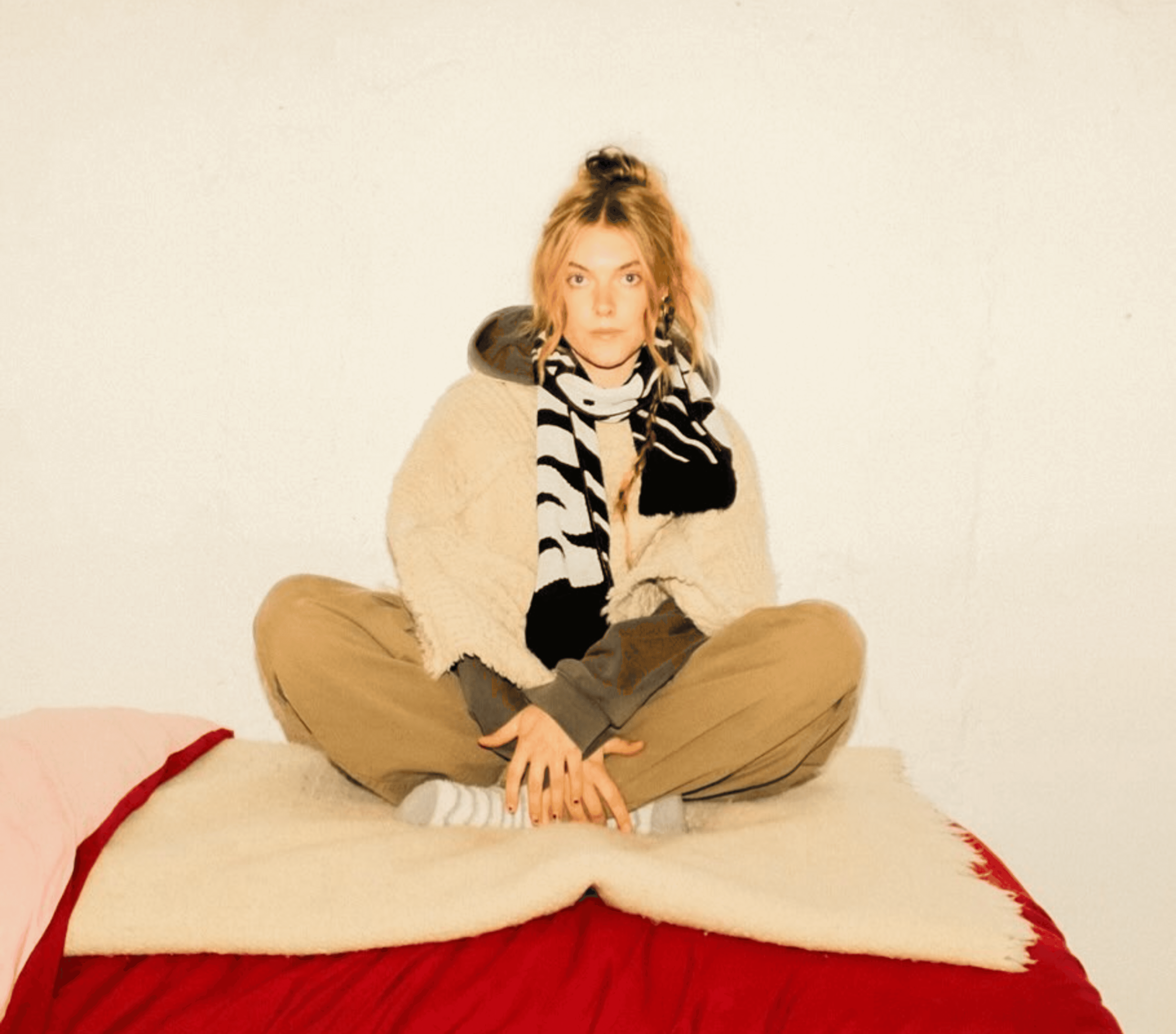 A woman sitting on a bed looking into the camera