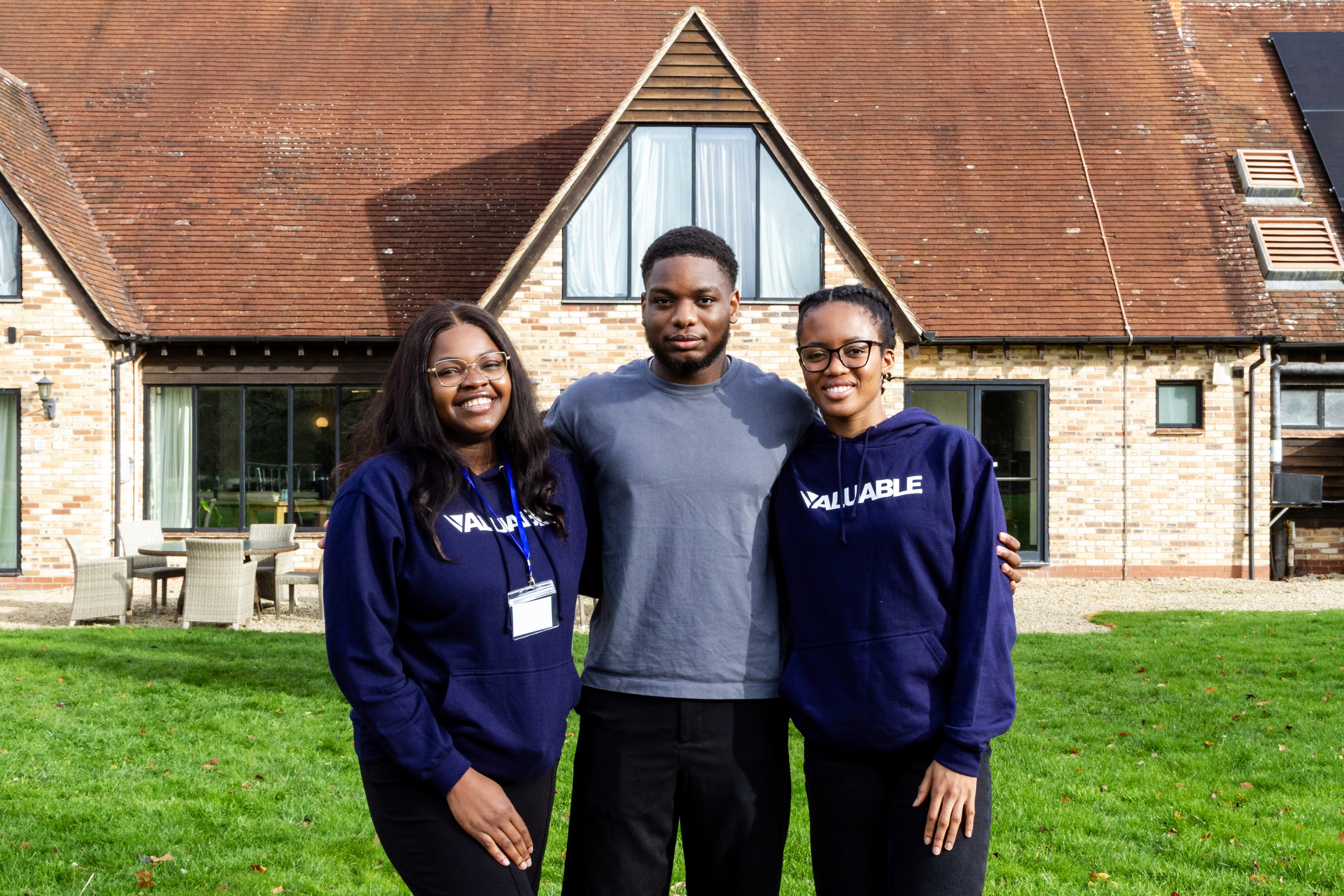 Three individuals outdoors smiling and posing for a photo. 