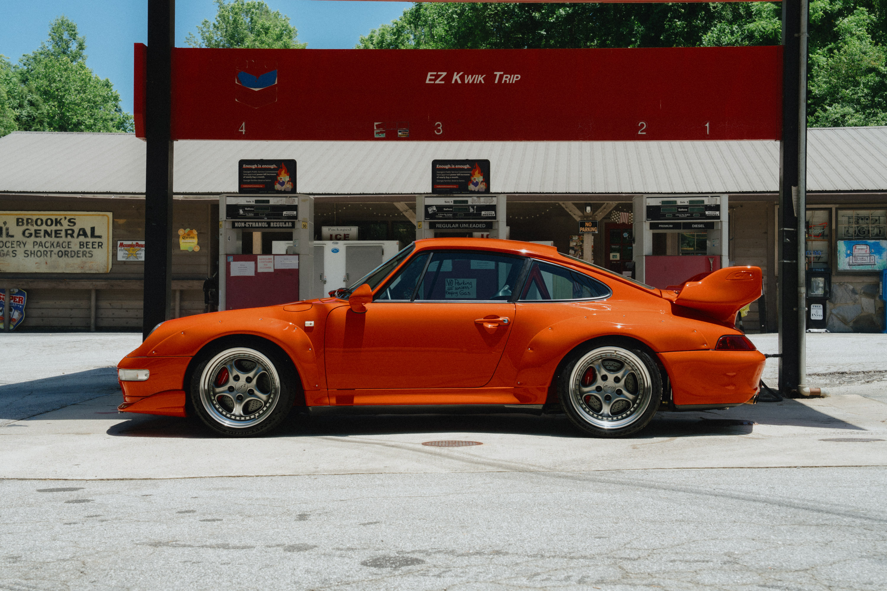 Blood Orange Porsche 993 GT2 parked at a vintage gas station