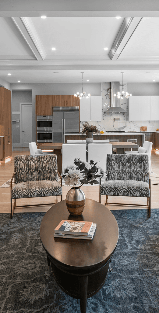 Modern living room with abstract art, beige sectional sofa, indoor plants, and large windows.