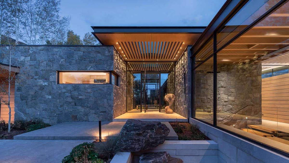Stone and timber residence with glass walls at dusk, architectural reference photograph