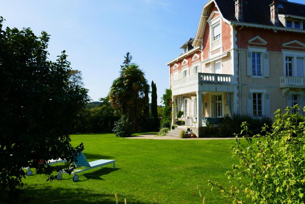 Classic two-story house with red and beige facade on a manicured green lawn.