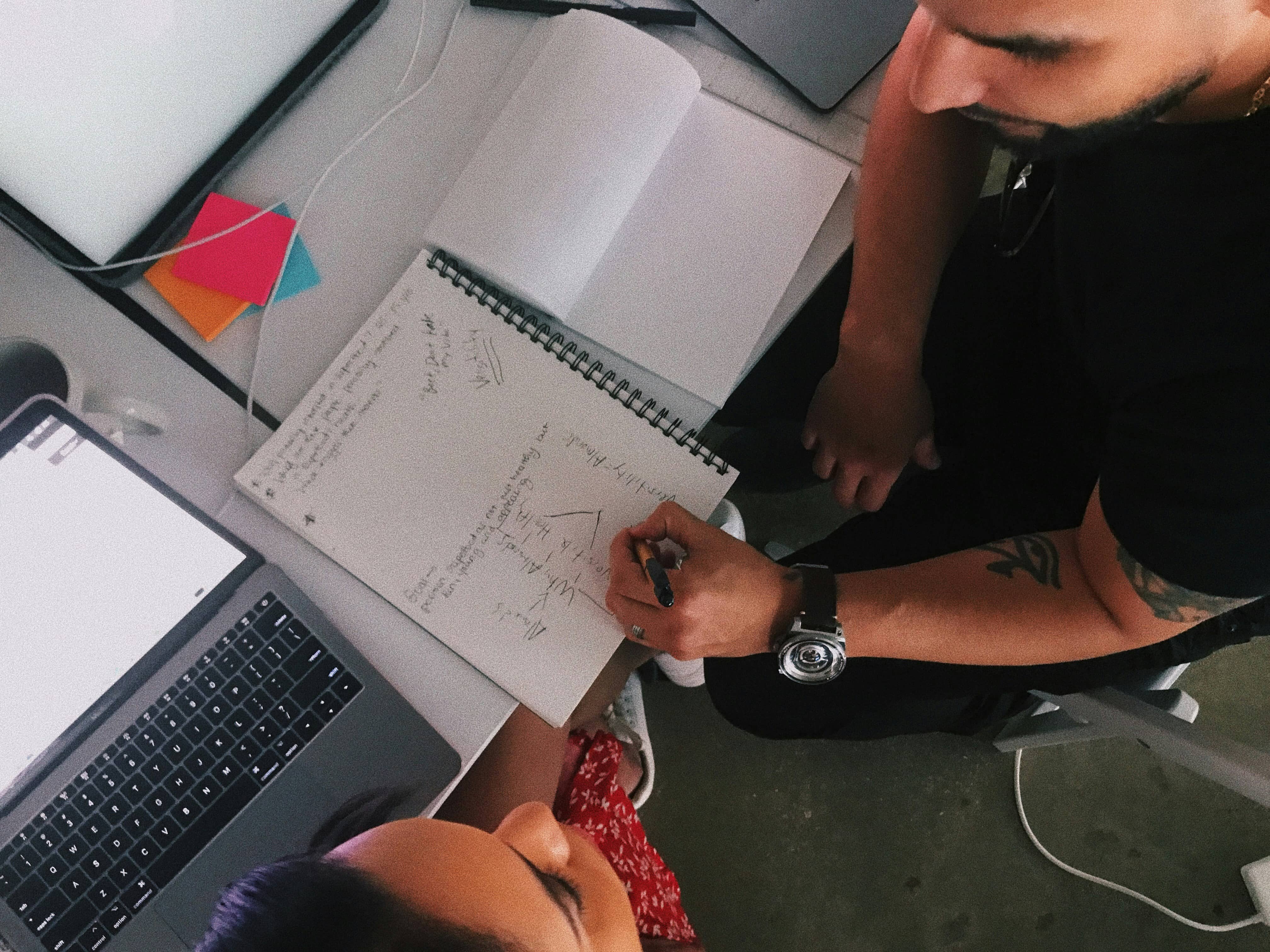 Two designers brainstorming logo ideas and sketching concepts for a great logo design.