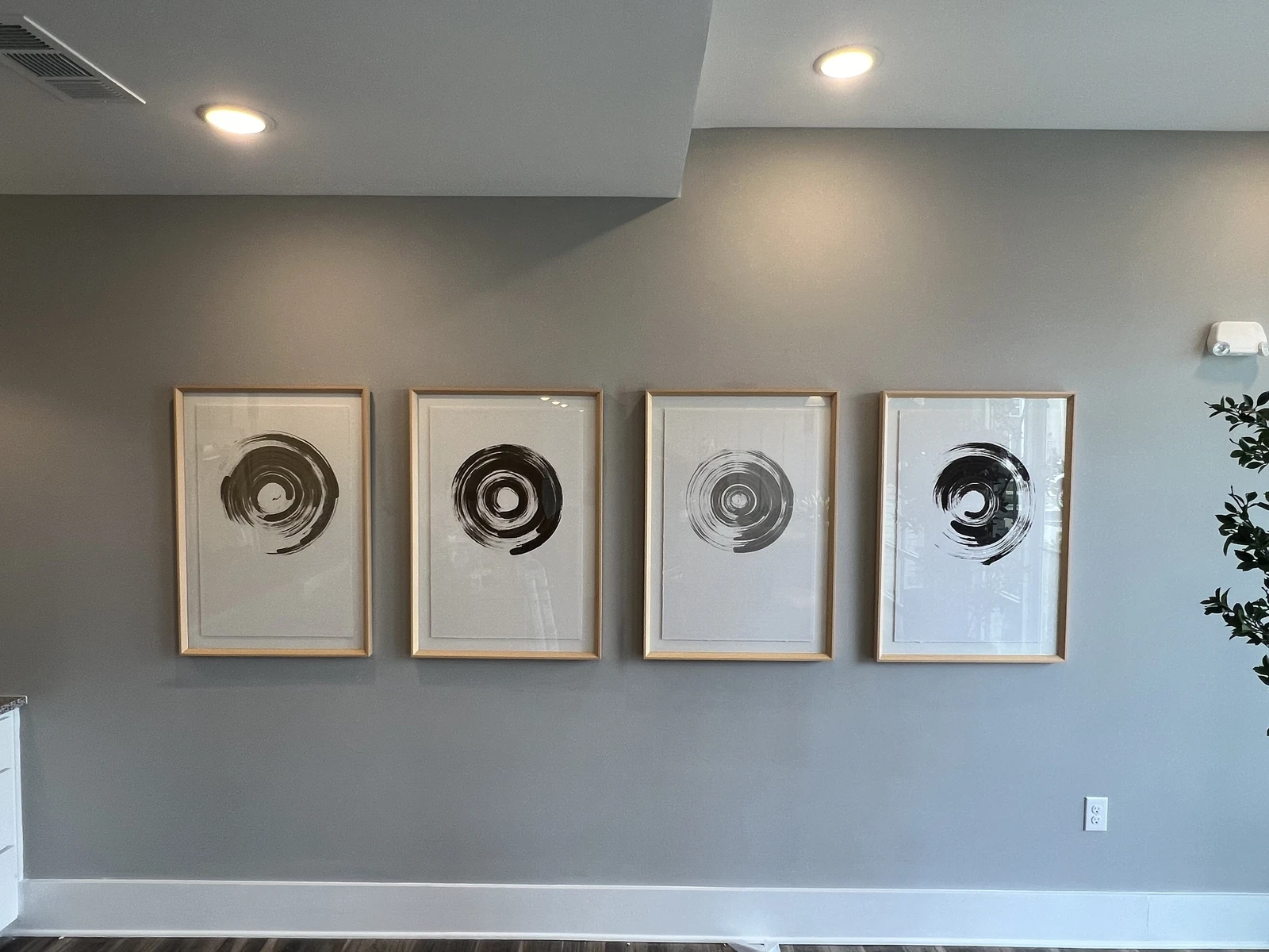 Four framed circular abstract prints aligned across a blue-gray wall.