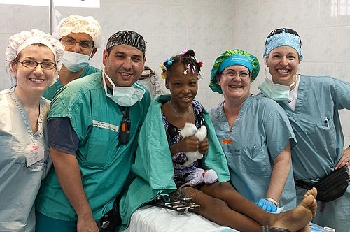 A diverse group of healthcare professionals smiles together in a hospital setting, celebrating a successful procedure.