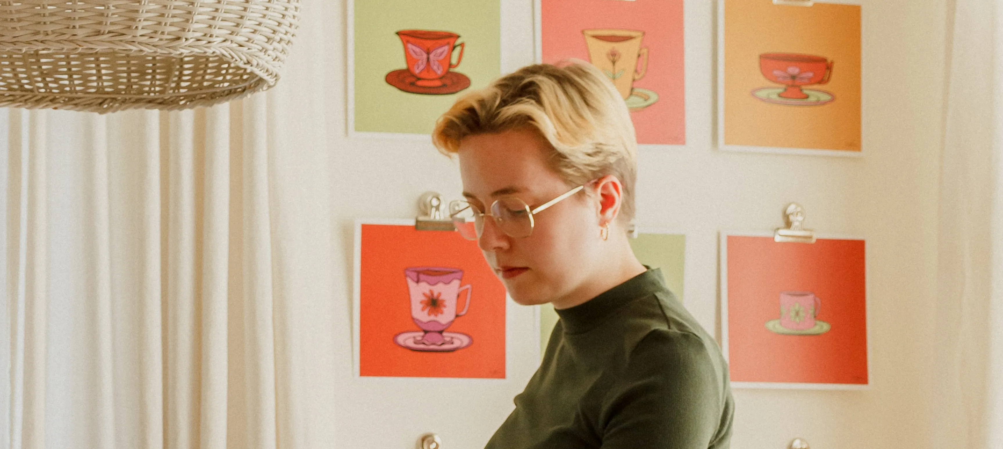 Emily Kiana standing in front of her prints hanging on the wall. 