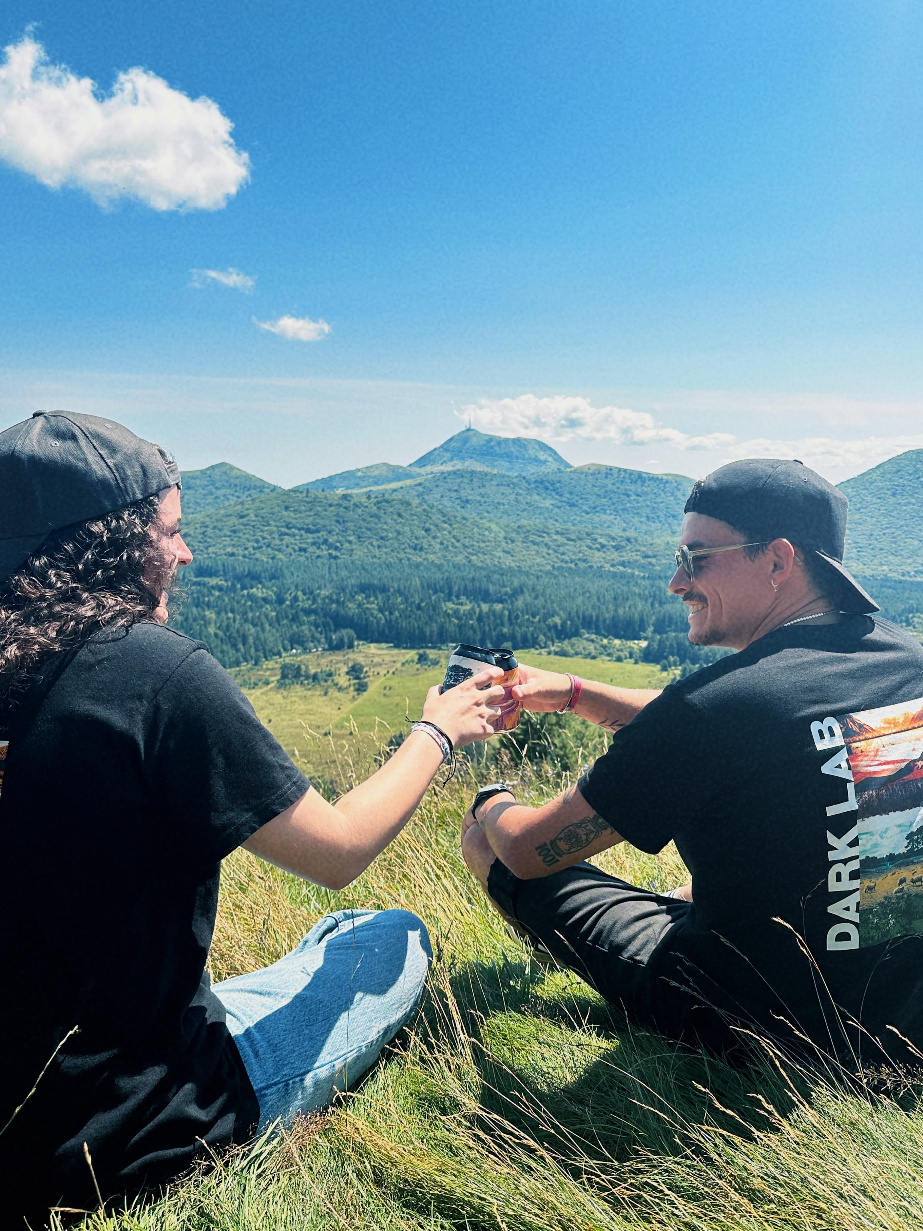 personnes trinquant avec une canette de bière devant la chaine des puys d'auvergne