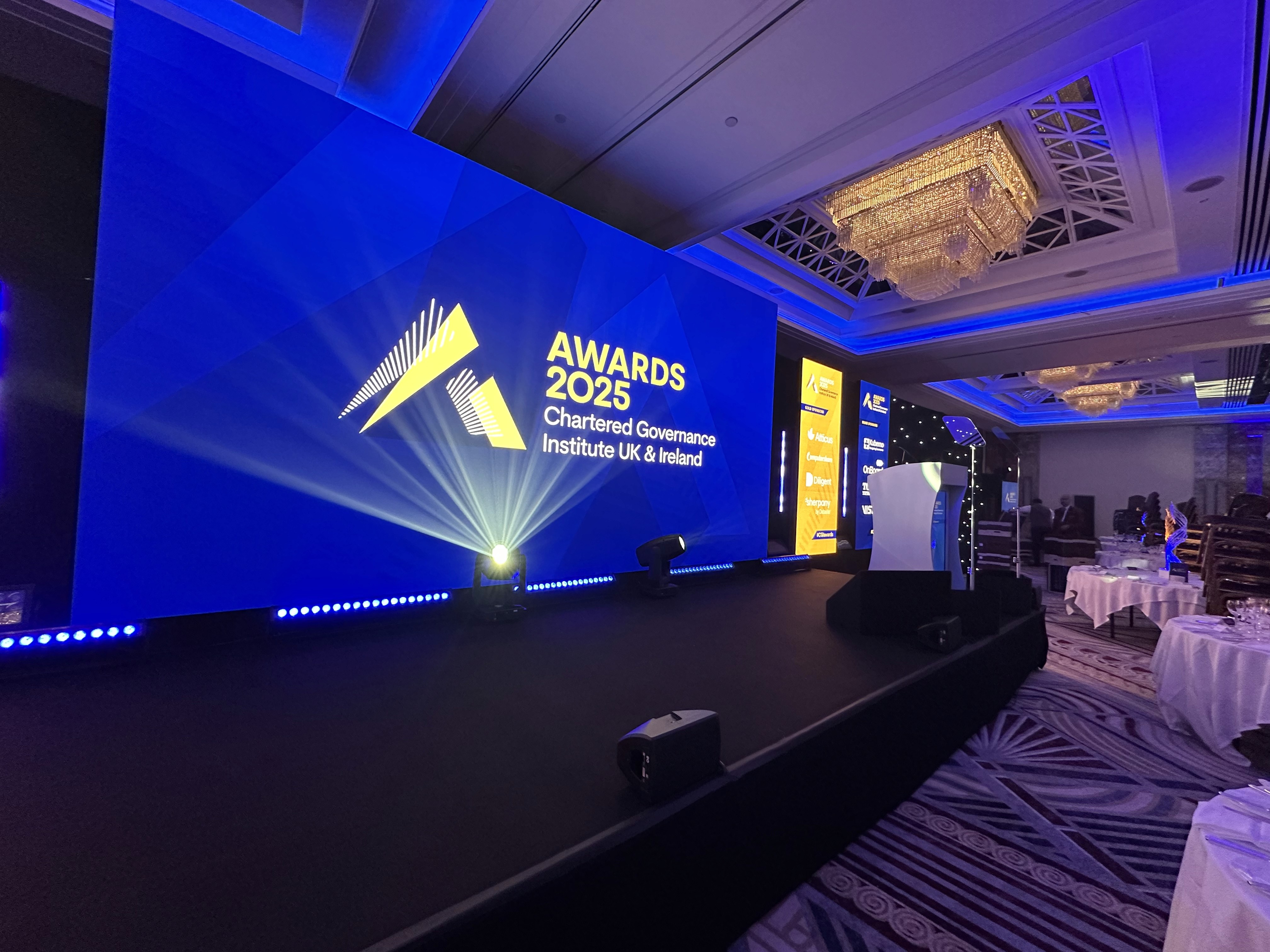 Side view of the CGI Awards stage with blue lighting, large-format LED and branded digital lectern.