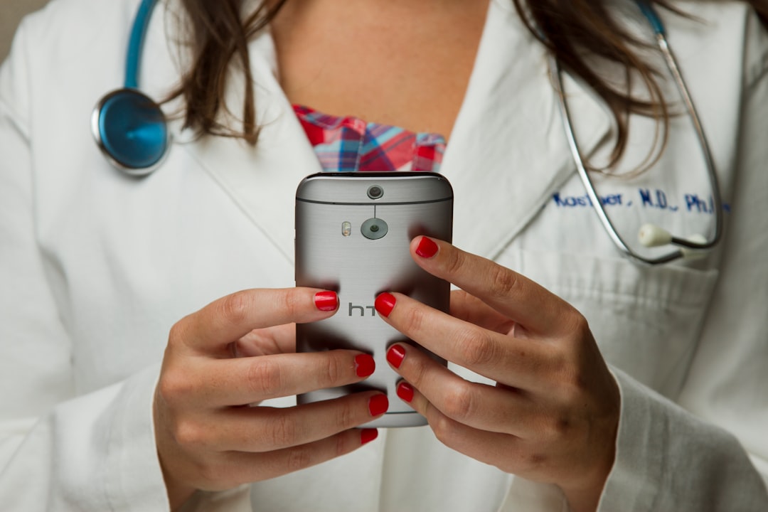 healthcare professional using a smartphone voice assistant in a brightly lit private office with plants and a window