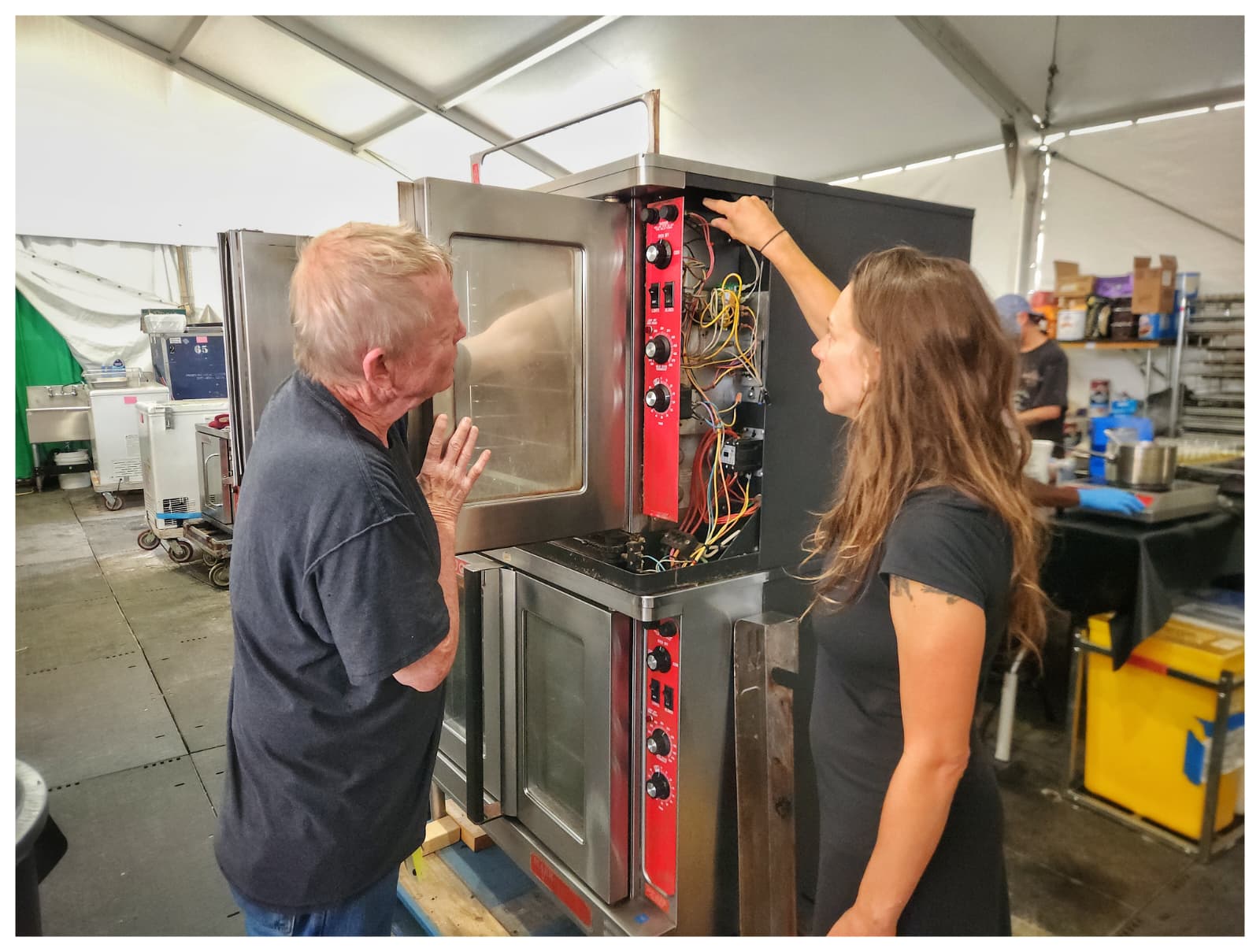 Two people are working together in a warehouse, unpacking boxes and organizing items in a workspace.