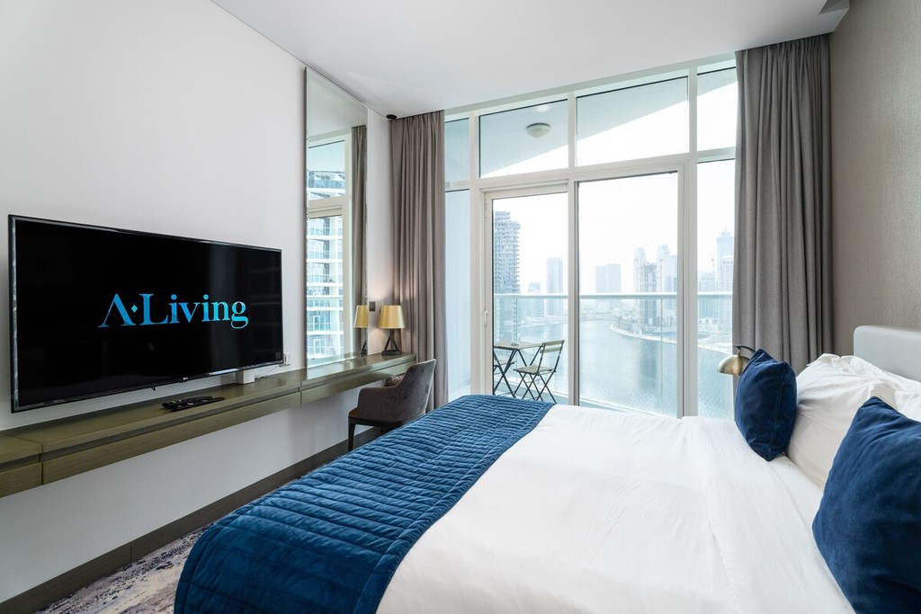 A living room featuring a large bed and a flat-screen TV, located in the Damac Maison Prive hotel.