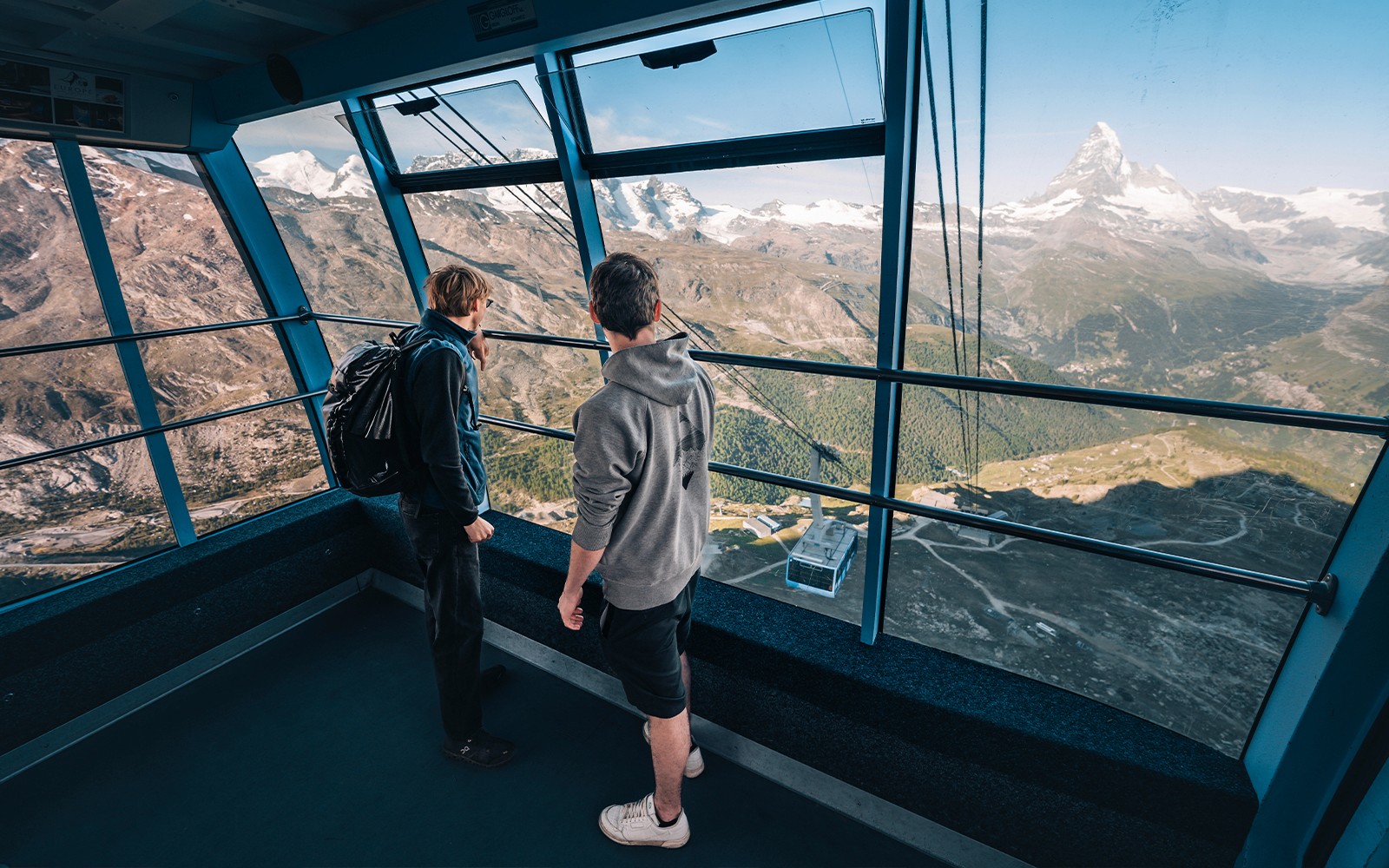 स्विट्जरलैंड के मैटरहॉर्न ग्लेशियर का दृश्य लेते हुए केबल कार के अंदर पर्यटक।