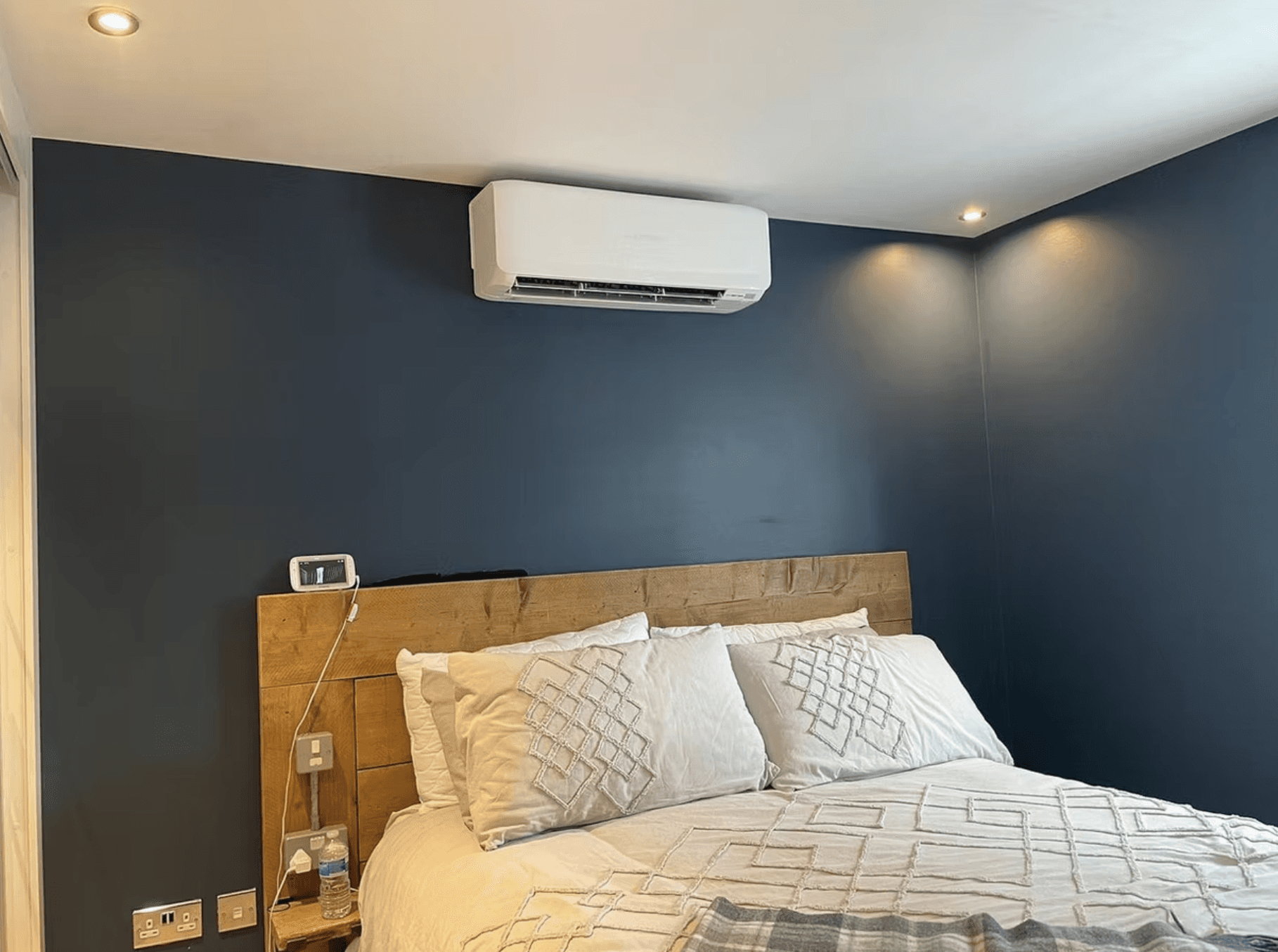 A modern house with large windows and a flat roof, surrounded by greenery against a clear blue sky.