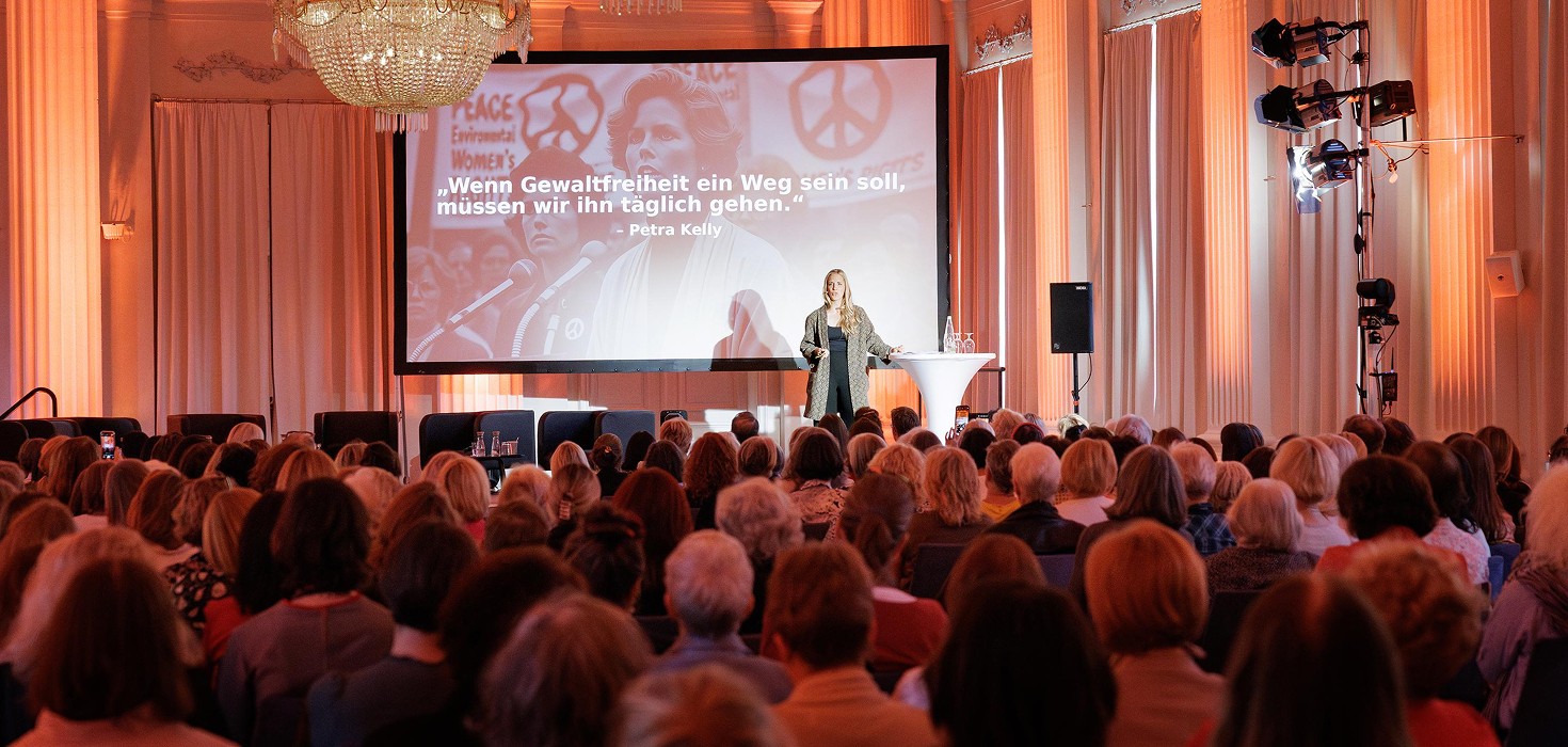 Caro Matzko steht vor einem Publikum und hält einen Vortrag.