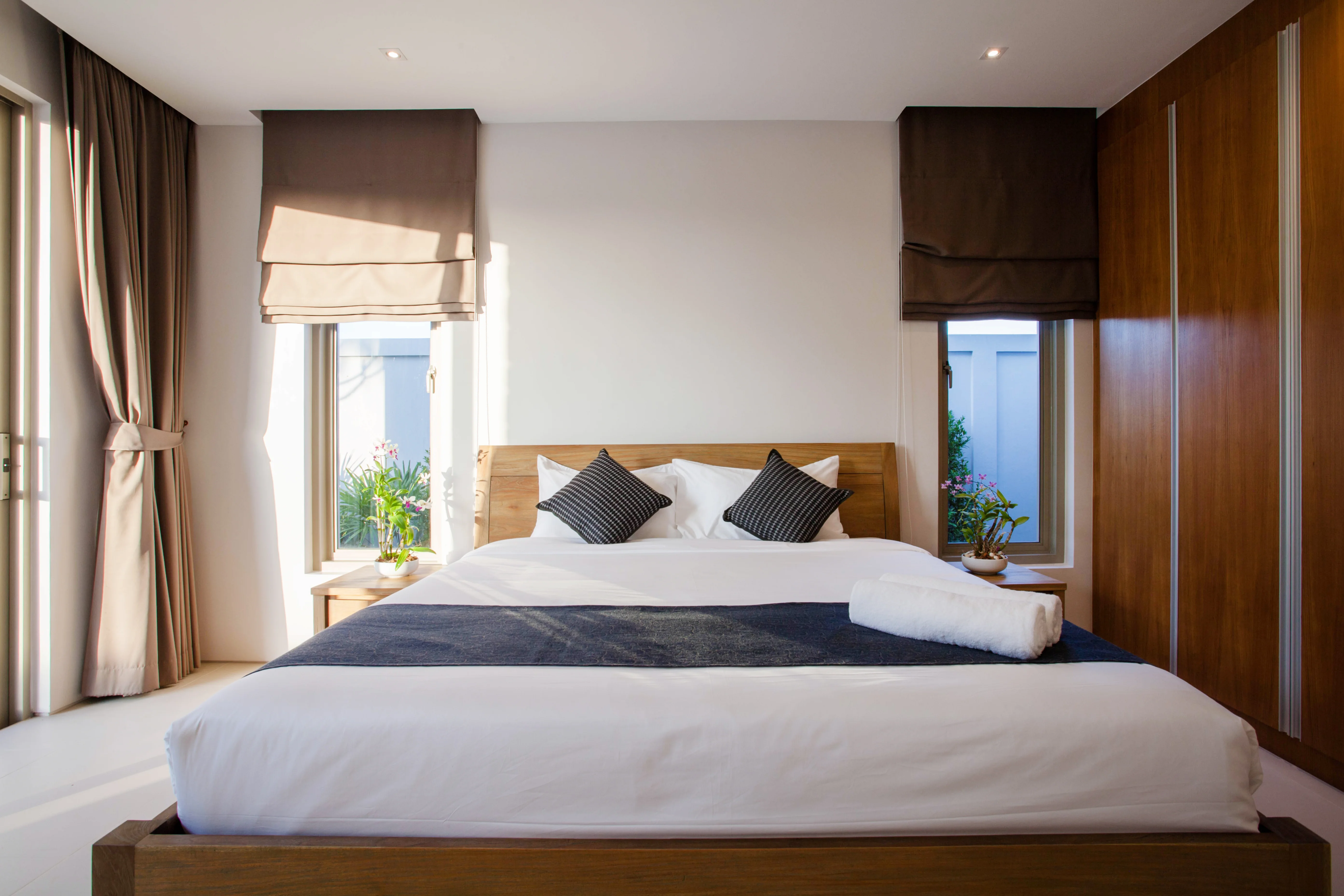 Bright minimal room with a teak bed and garden windows