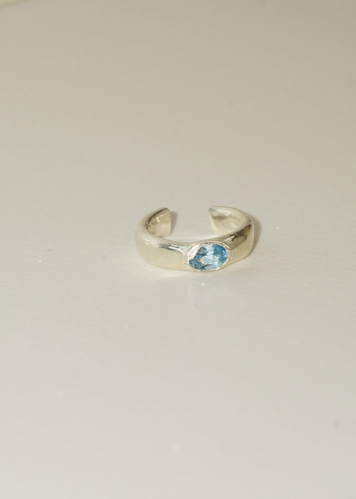 Silver ring with a blue gemstone on a light gray background
