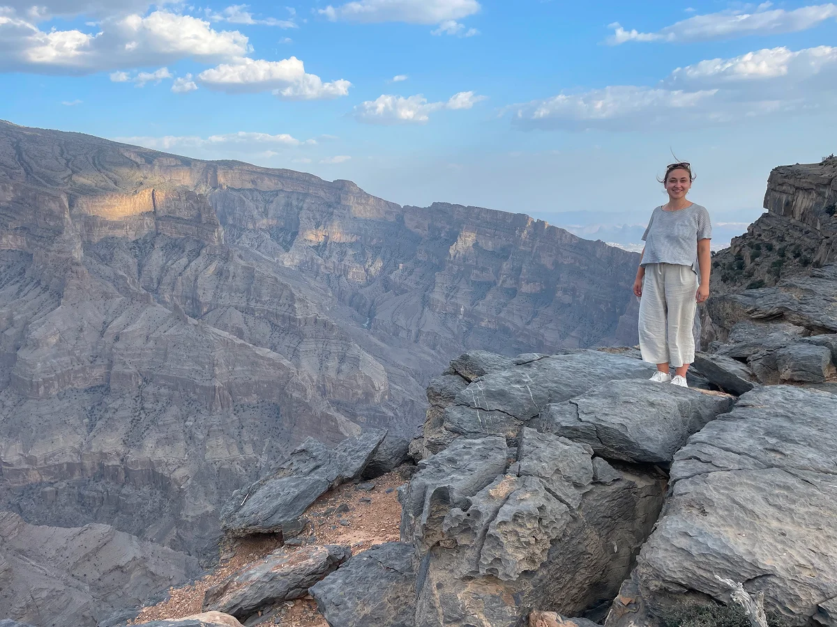 Frau steht an Klippe mit Panorama auf Berg
