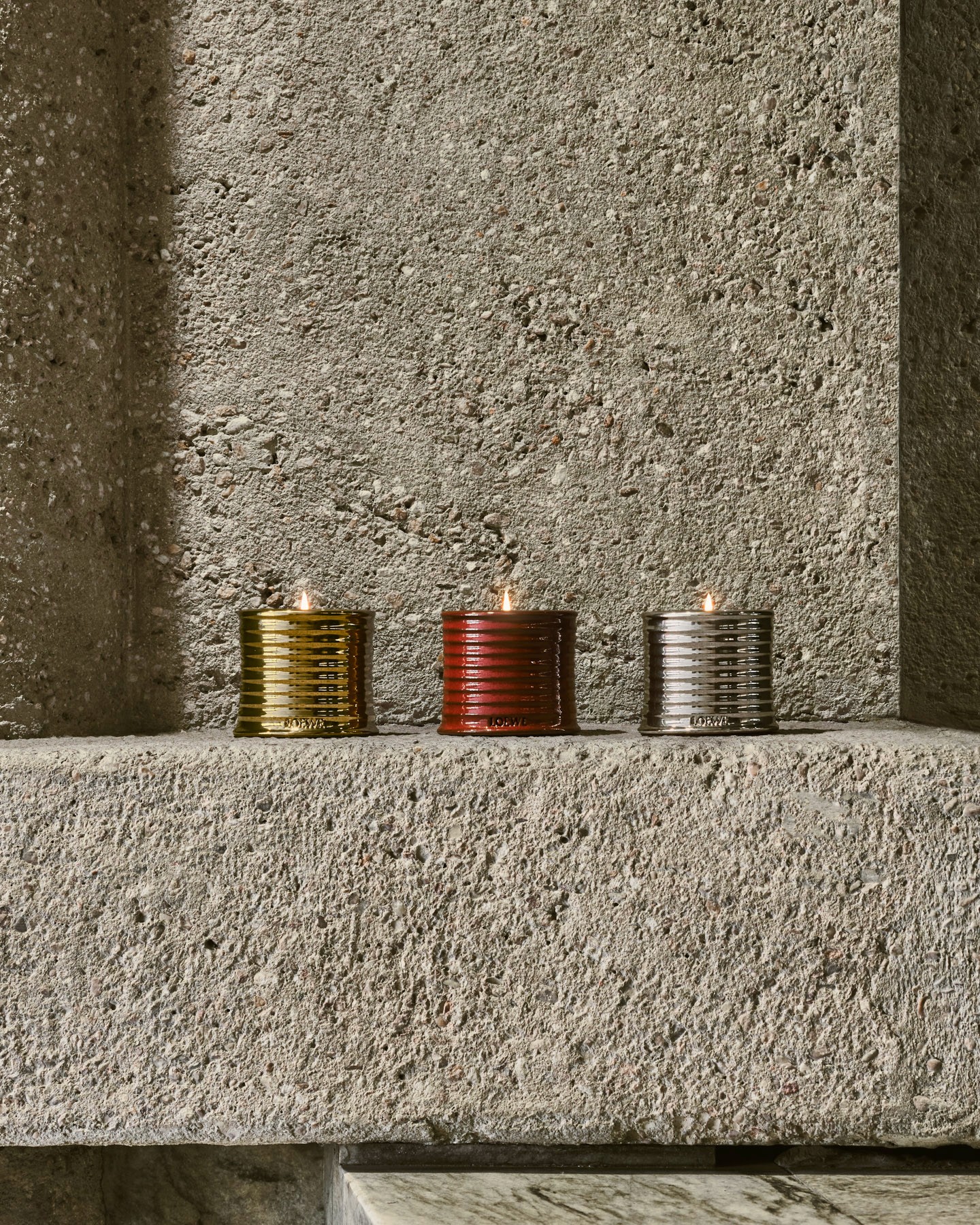The LOEWE Home Scents candle collection photographed within the brutalist concrete interiors of Estudio Lamela, Madrid.