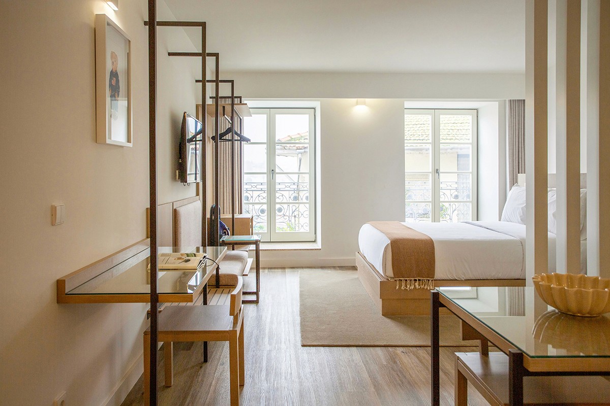 a hotel room with a bed, desk, chairs and a television