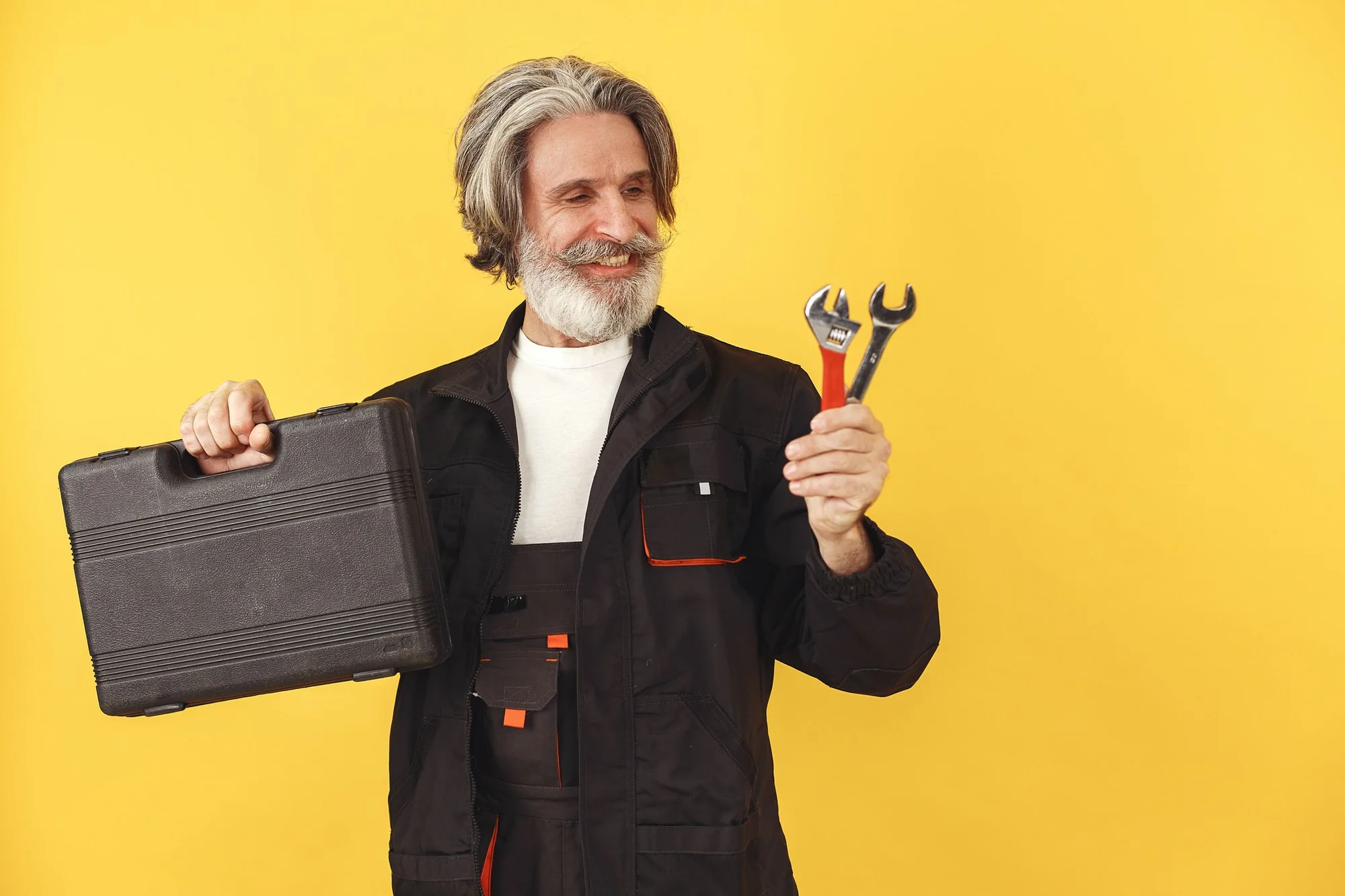 A smiling tradesman holding two wrenches